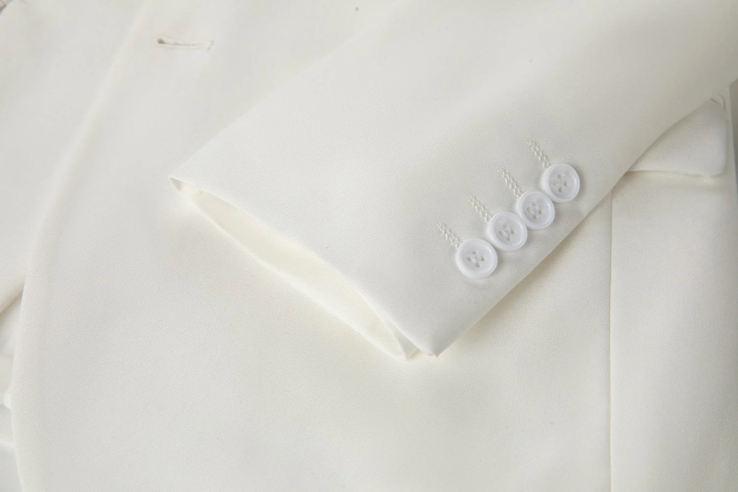Men's ivory two button blazer cuff detail - four white round buttons with stitched buttonholes on smooth ivory fabric