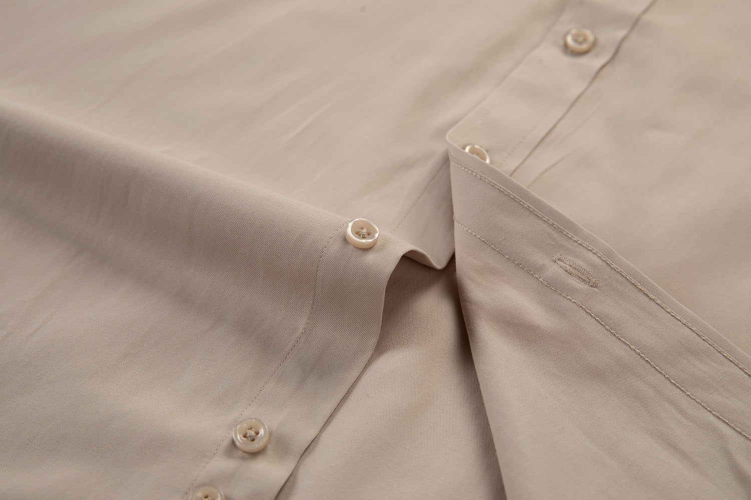 Close-up of champagne shirt buttons and fabric – subtle sheen with modern tailoring