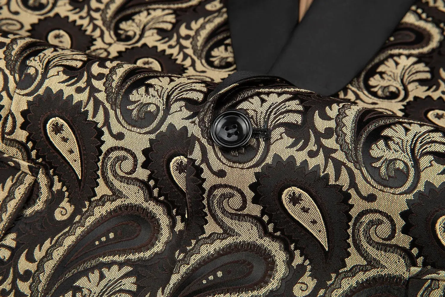 A close-up of a black paisley-patterned men's blazer showing the detailed fabric with a black button fastening, showcasing the fine craftsmanship and luxurious design.