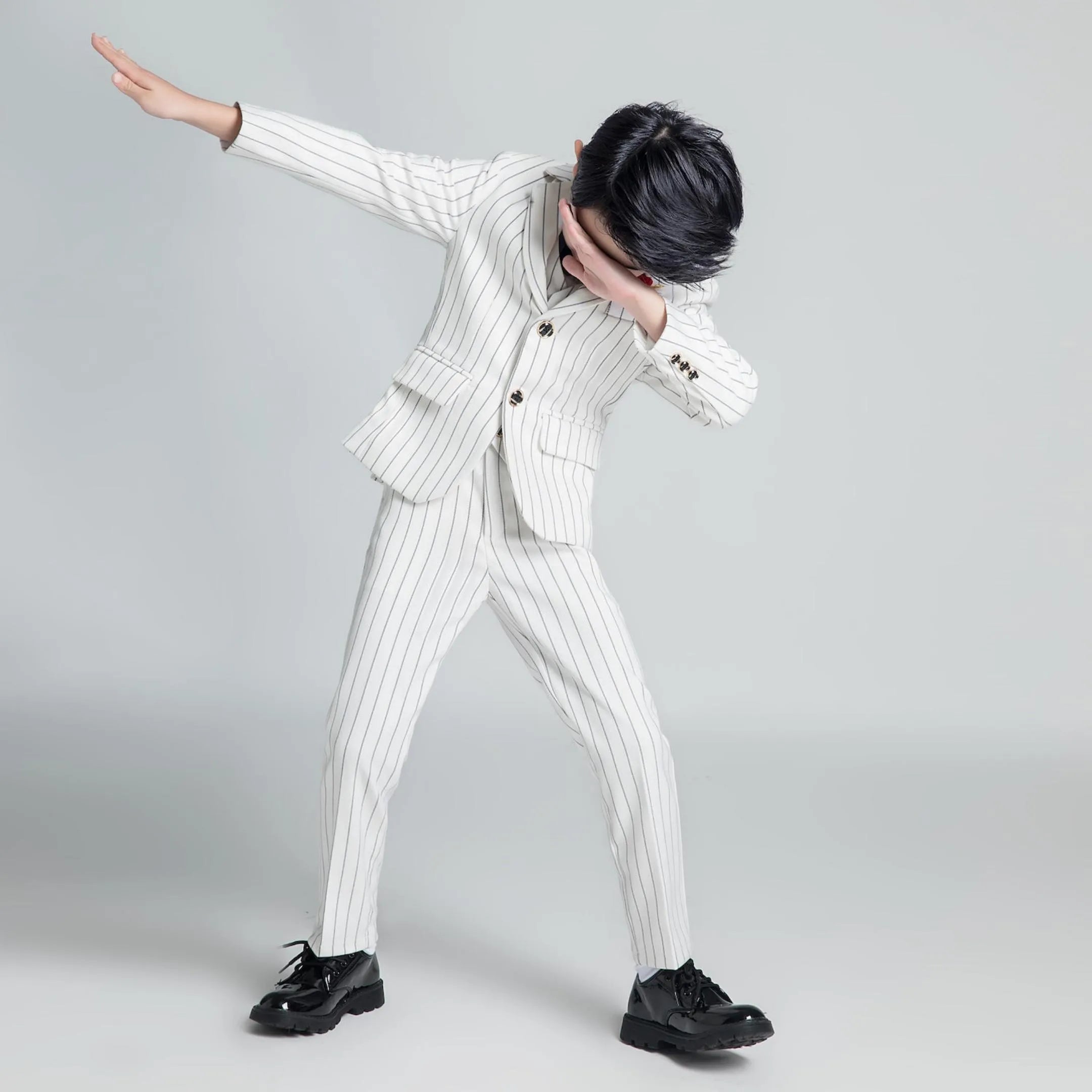Playful pose in white striped boys suit, modern formal outfit