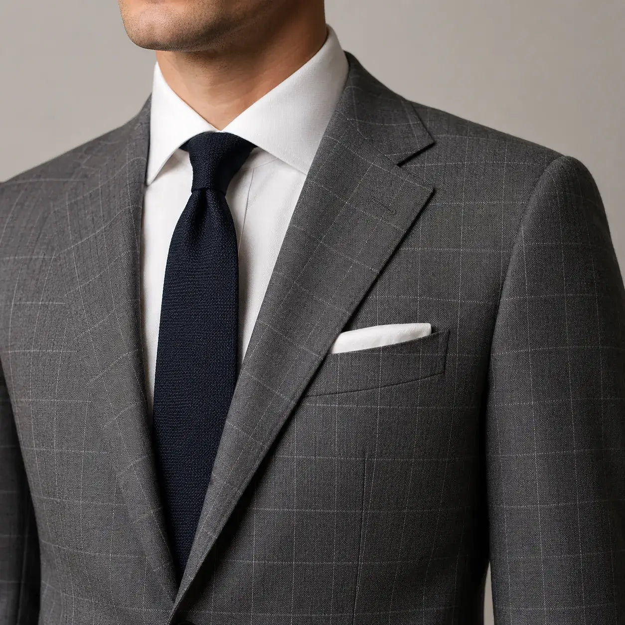 Close-up of a men's grey checked suit showing a regular grid pattern and tailored details.