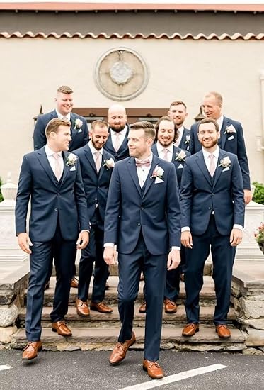 Groomsmen in navy blue suits with pink ties, groom in polka dot bow tie, walking down stone steps at wedding