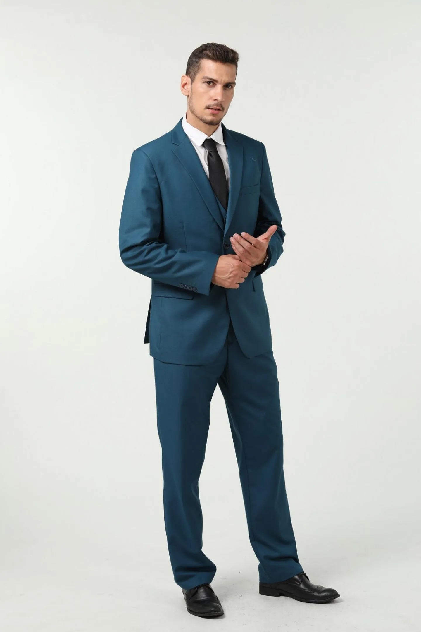 full body view of a man in a lake blue slim fit two-button 3-piece suit, standing confidently while adjusting the front of his jacket.