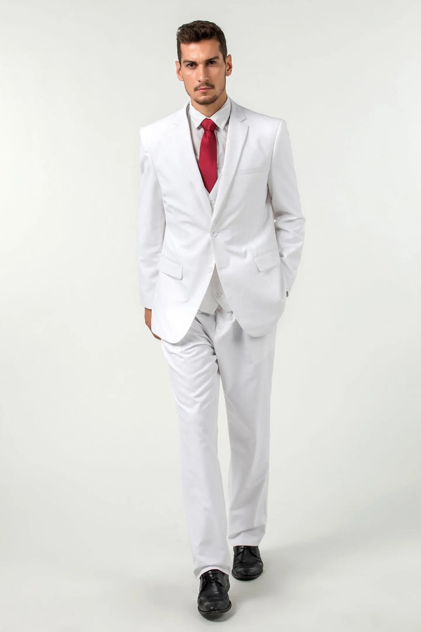 full-body view of a man wearing a white slim fit two-button 3-piece suit with a red tie, walking confidently.