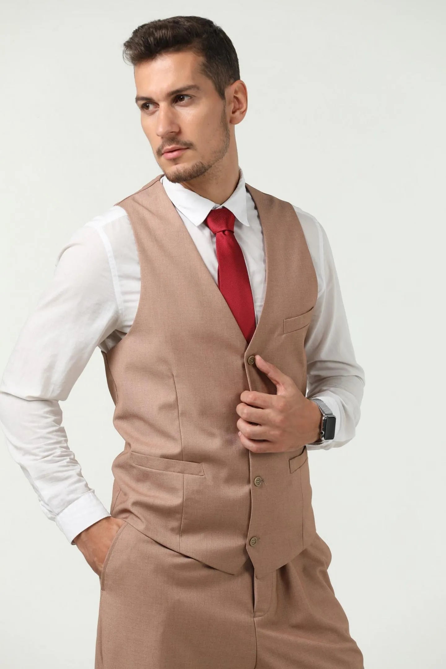 model in a champagne colored men's slim fit vest and pants, paired with a red tie, side view.