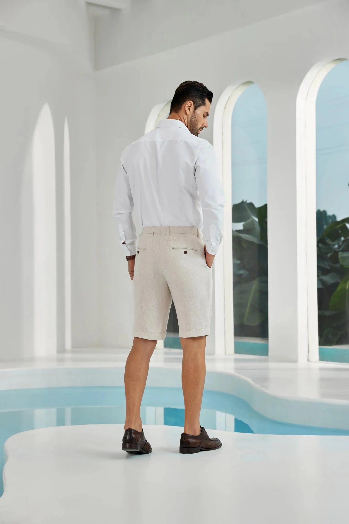 back view of beige linen shorts for men – slim fit tailored summer casual wear paired with white shirt and dress shoes