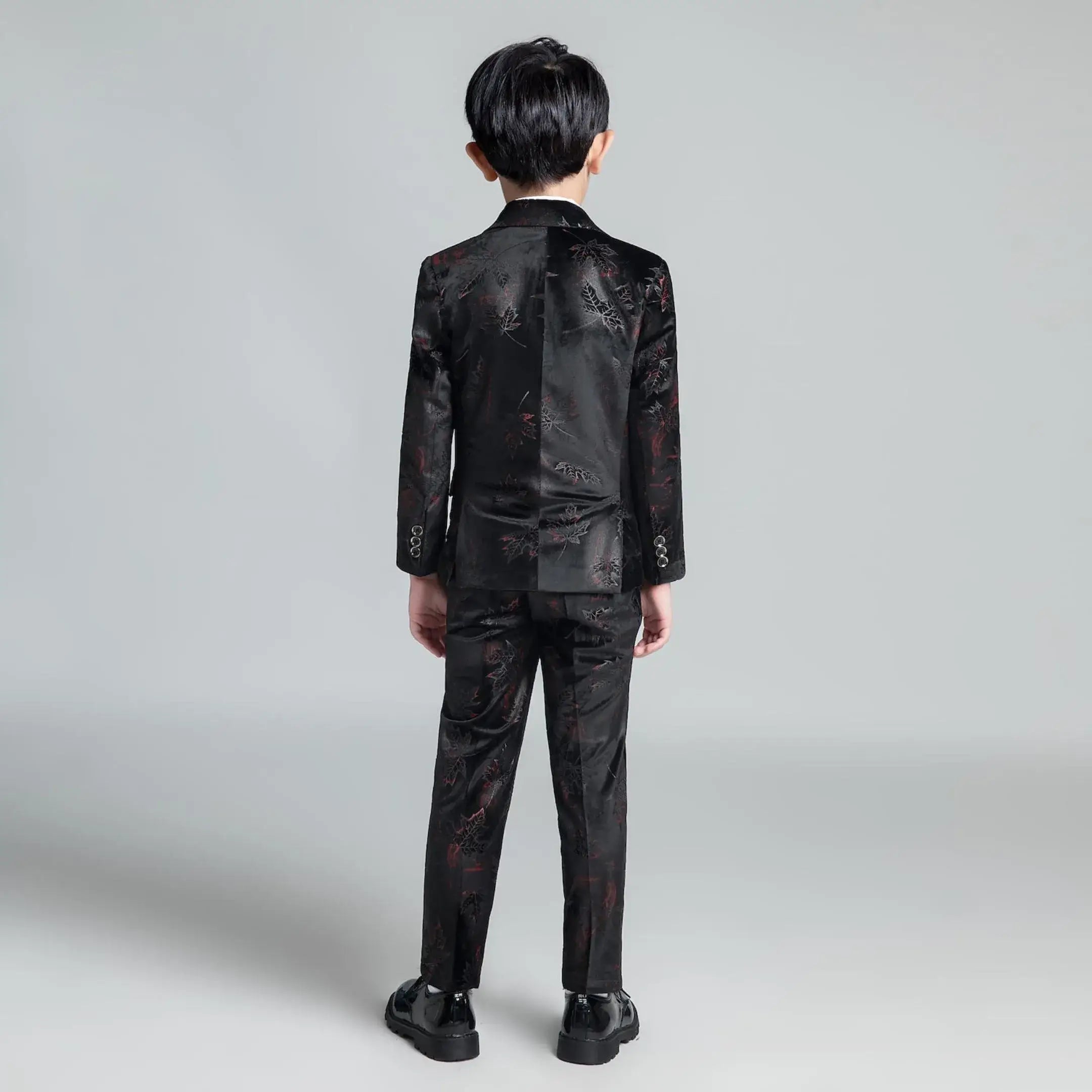 Back view of black floral boys' suit with shiny fabric and slim tailoring, ideal for formal occasions or graduation