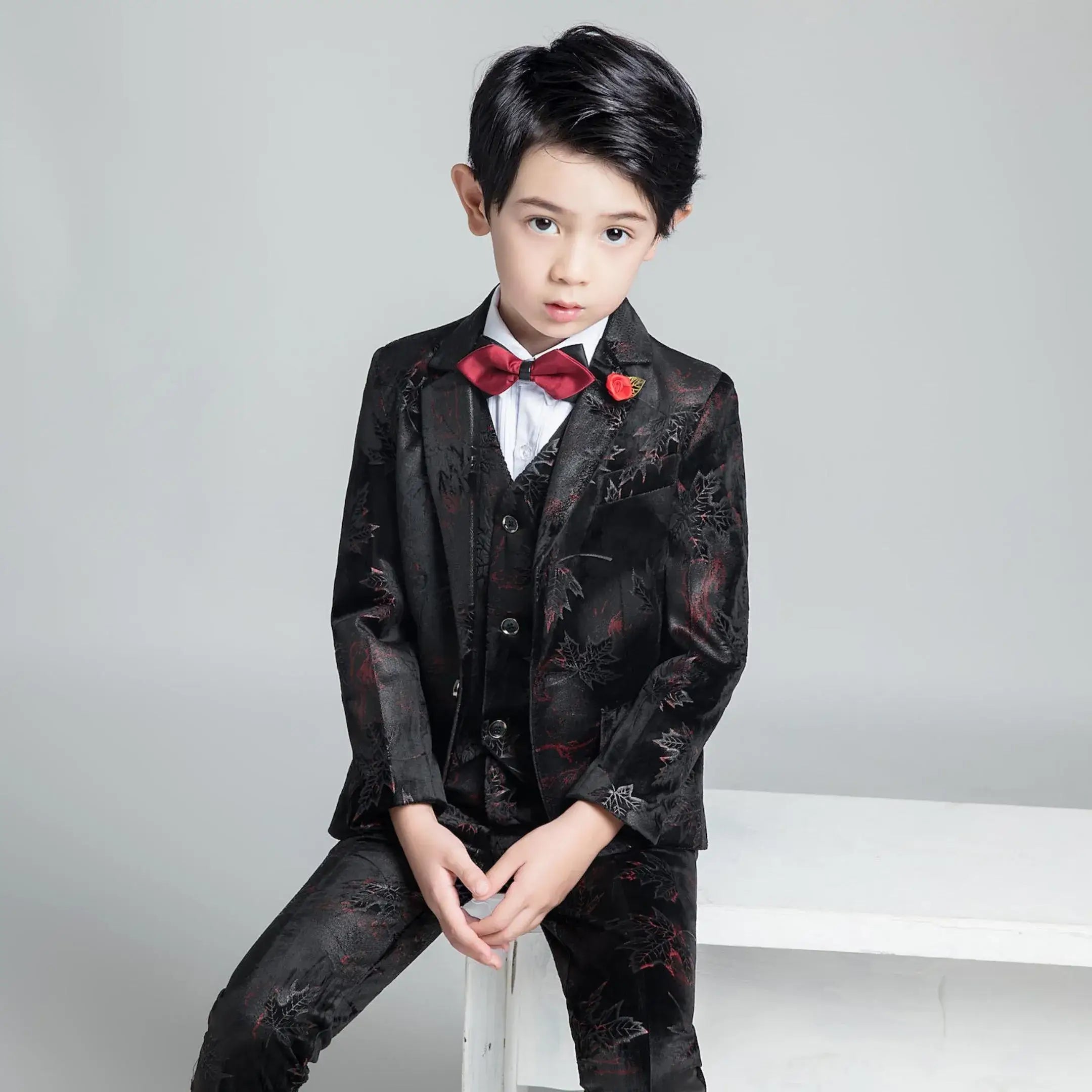 Chic black floral boys' suit with red bow tie and rose pin, stylish slim fit look for graduation or party event