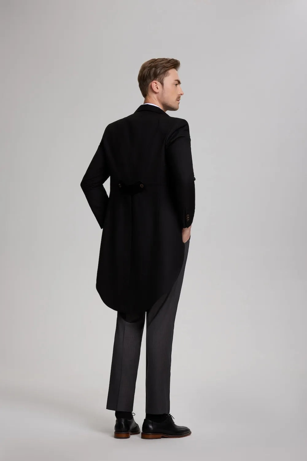 Rear view of the men's formal evening suit, highlighting the classic long tails of the black tailcoat jacket.