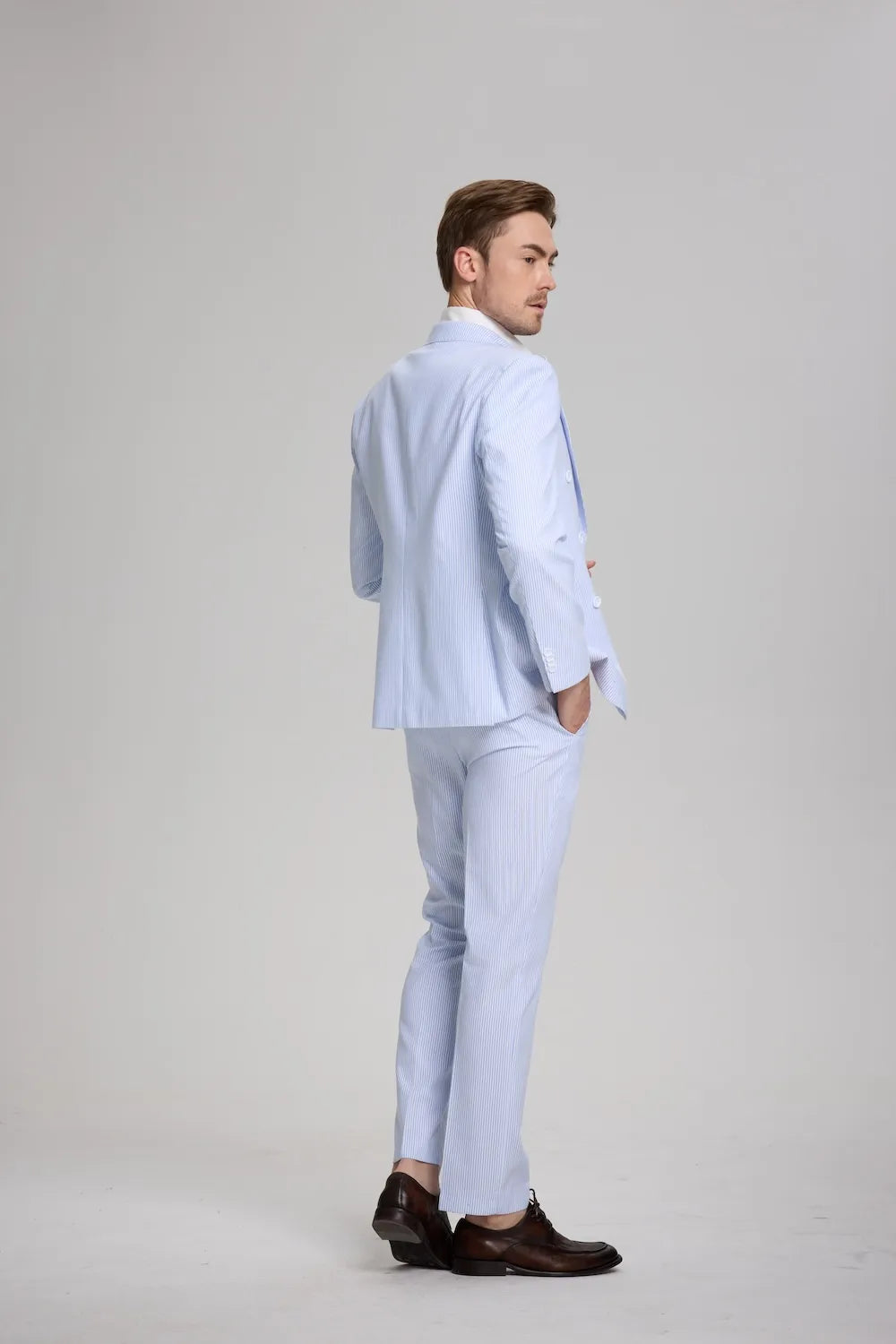 Back angle of blue striped 3-piece seersucker suit with hands in pockets