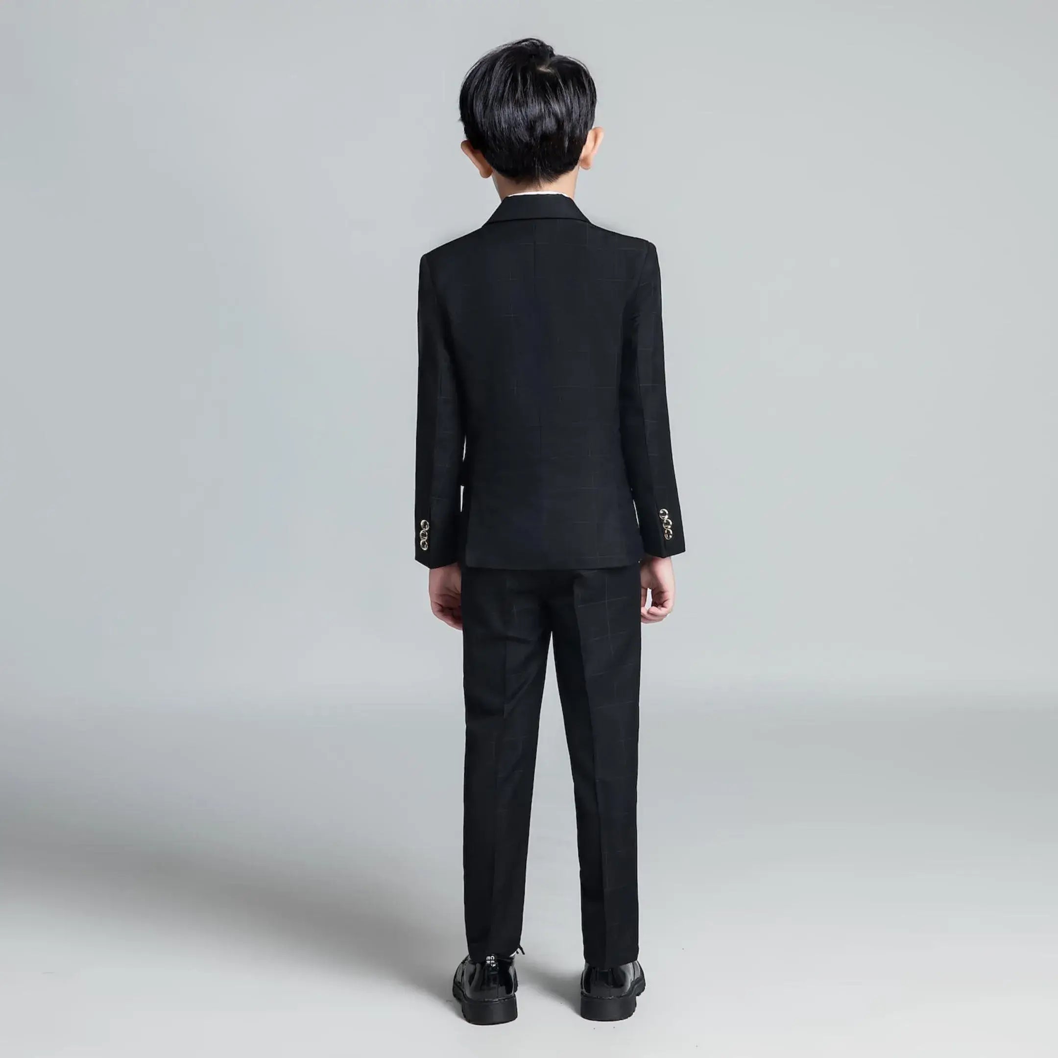 Back view of black plaid boys' formal suit with fitted blazer and straight-leg trousers