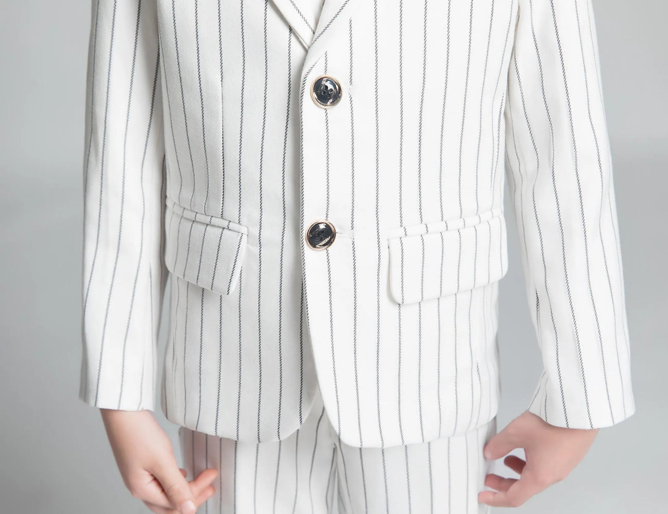 Lower front view of white stripe suit jacket and pants with gold button detail – modern boys formal outfit
