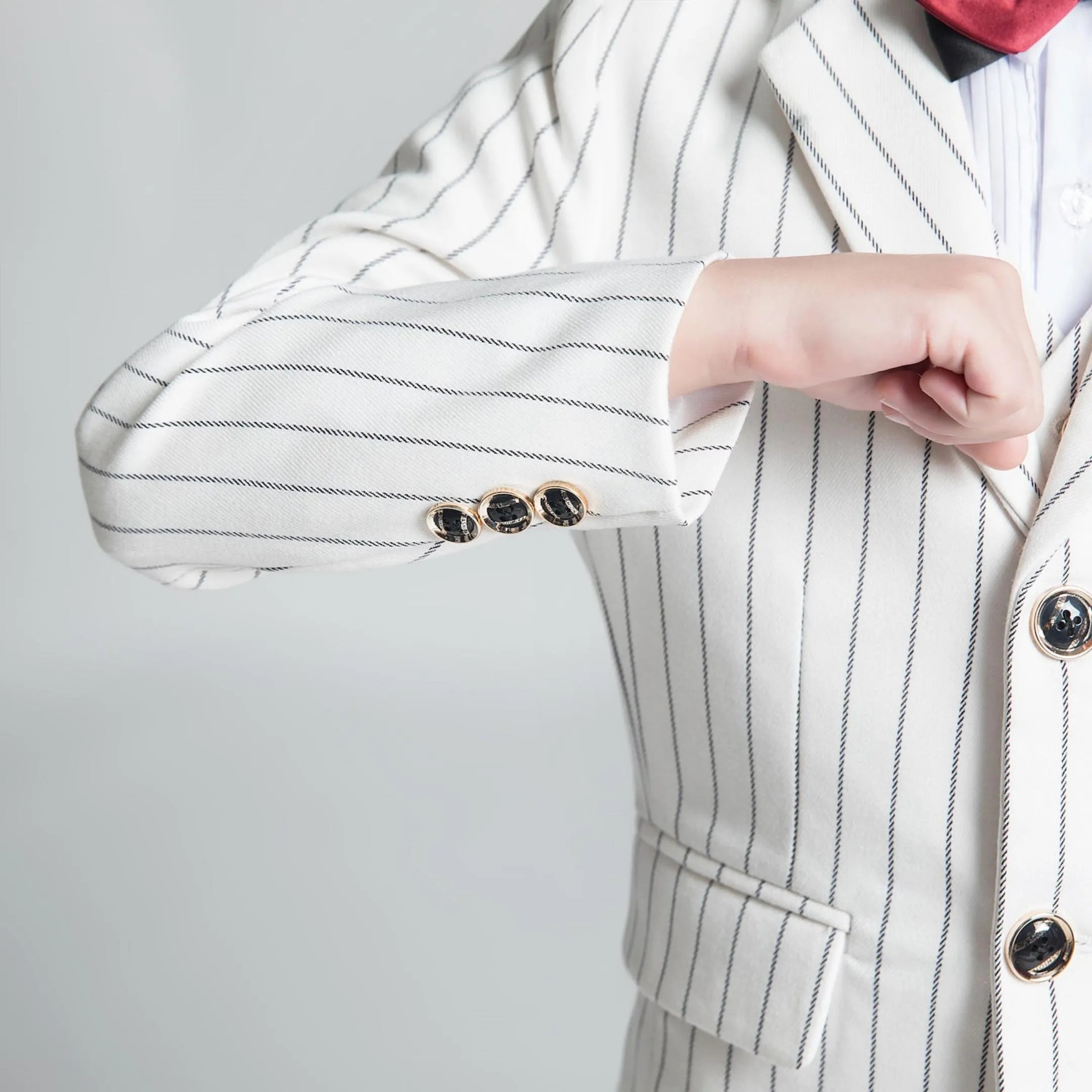 Close-up of white striped blazer sleeve with decorative buttons – elegant boys formalwear detail