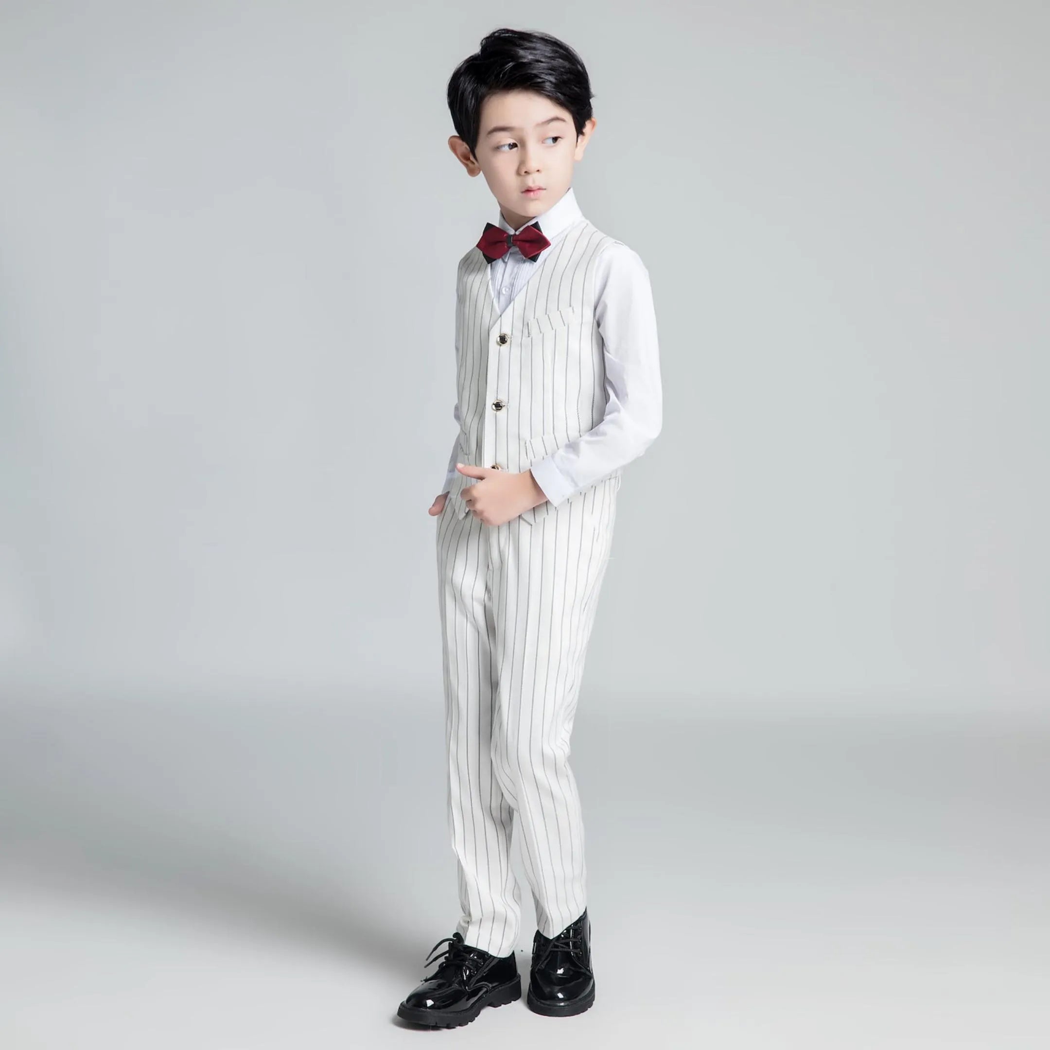 Side profile of boys white striped vest suit with red bow tie