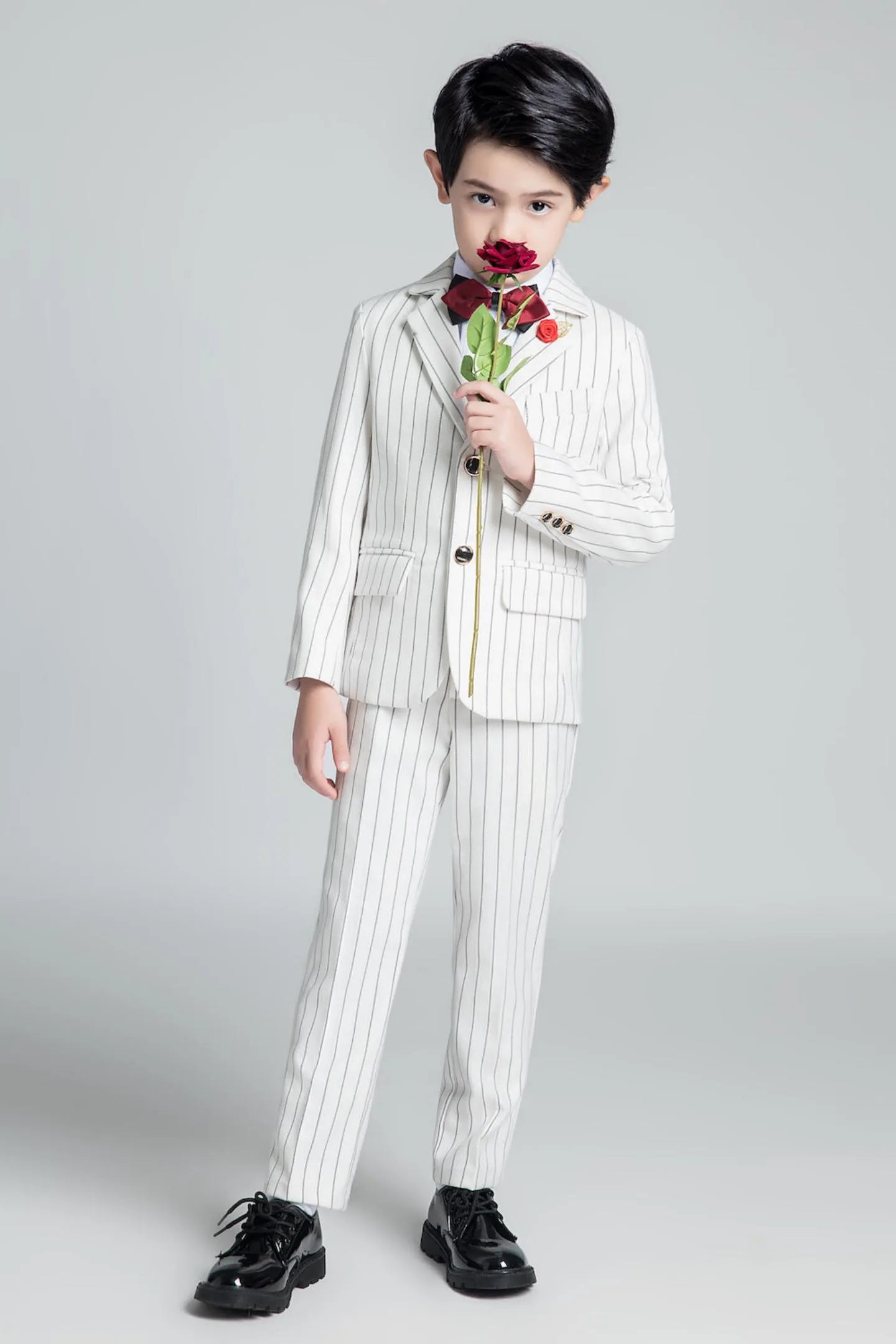 White pinstripe 5 piece boys suit with red bow tie and rose, elegant pose