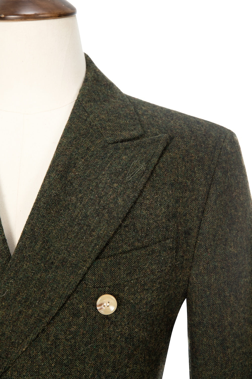 Close-up on peak lapel and button of green wool dress coat – textured fabric detail