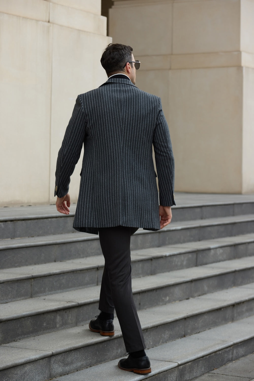Back view of men’s grey trench coat – walking up stairs in a tailored overcoat