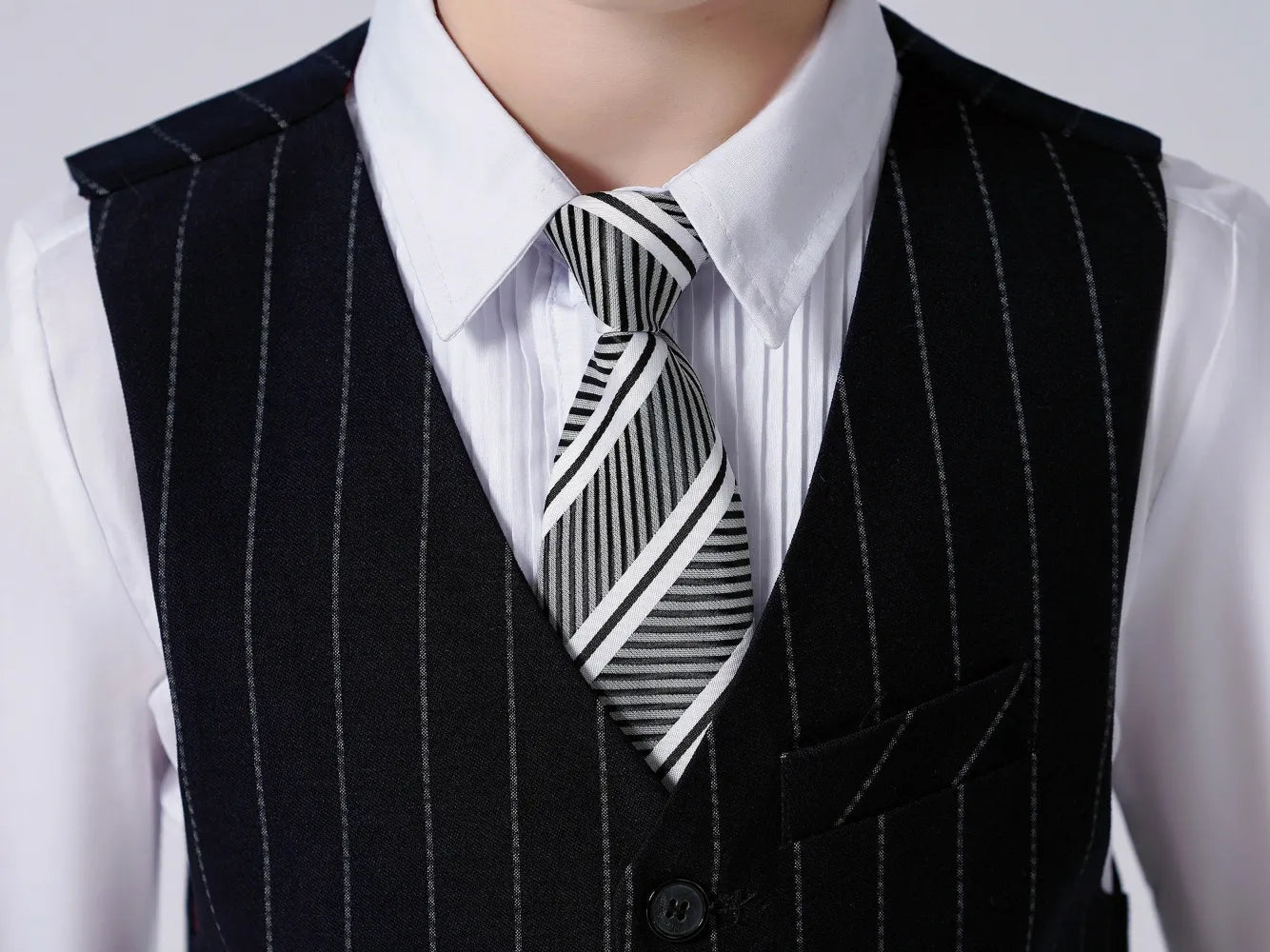 Close-up of striped tie and navy pinstripe vest – stylish suit details for boys’ wedding attire
