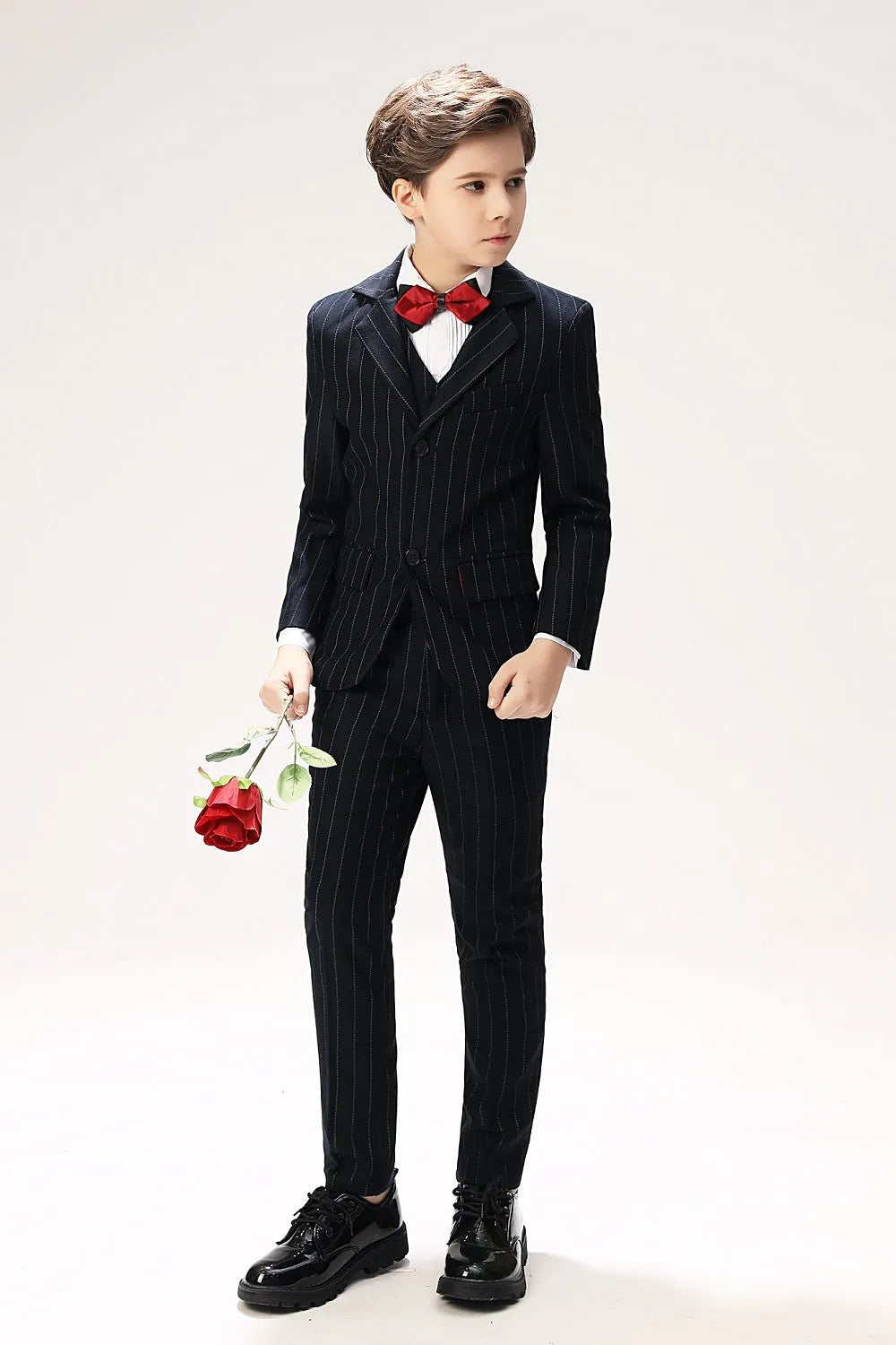 Modern boy's pinstripe suit with red bow tie and single-breasted jacket – formal outfit with roses
