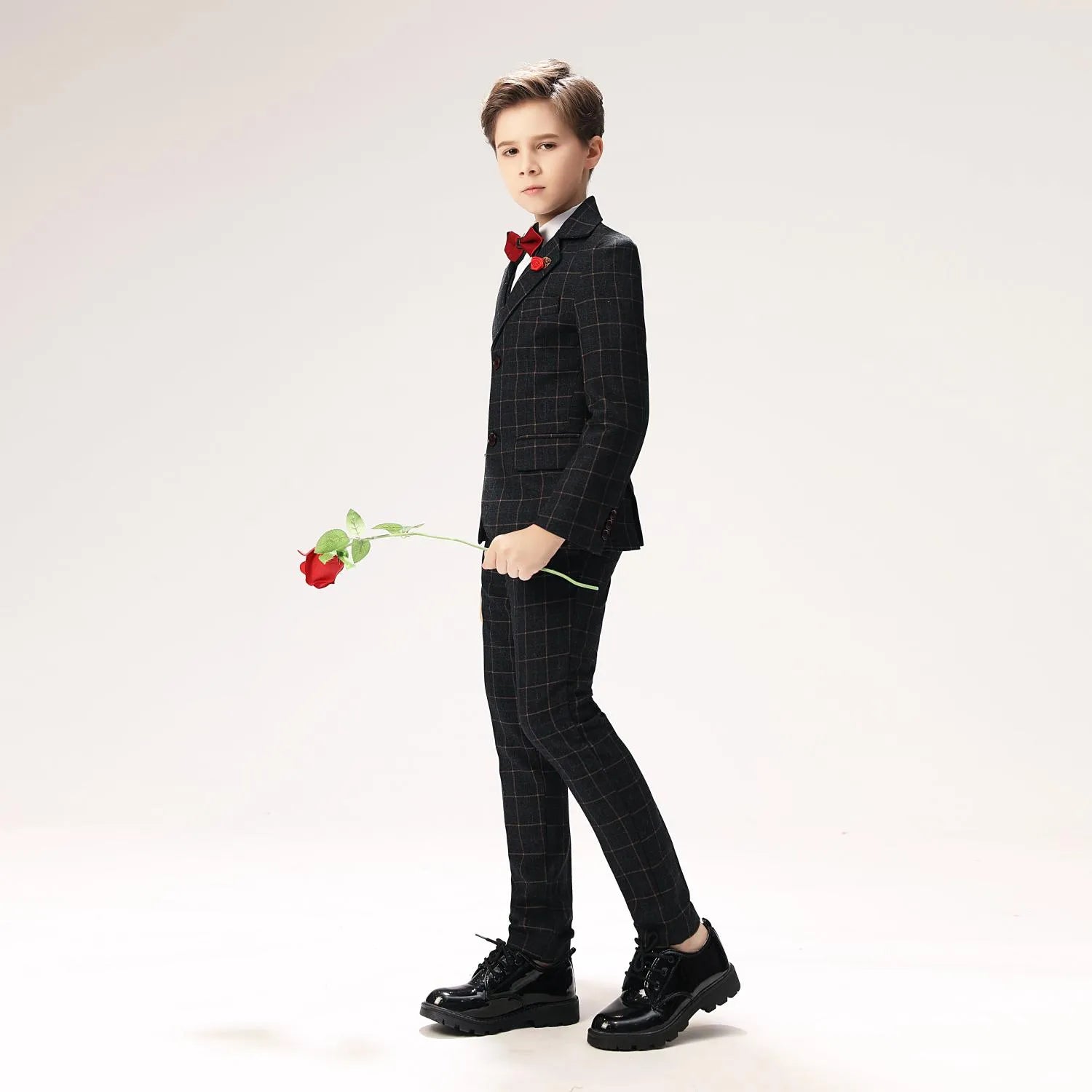 Little boy in tailored black checkered suit holding rose, ideal ring bearer outfit for formal events