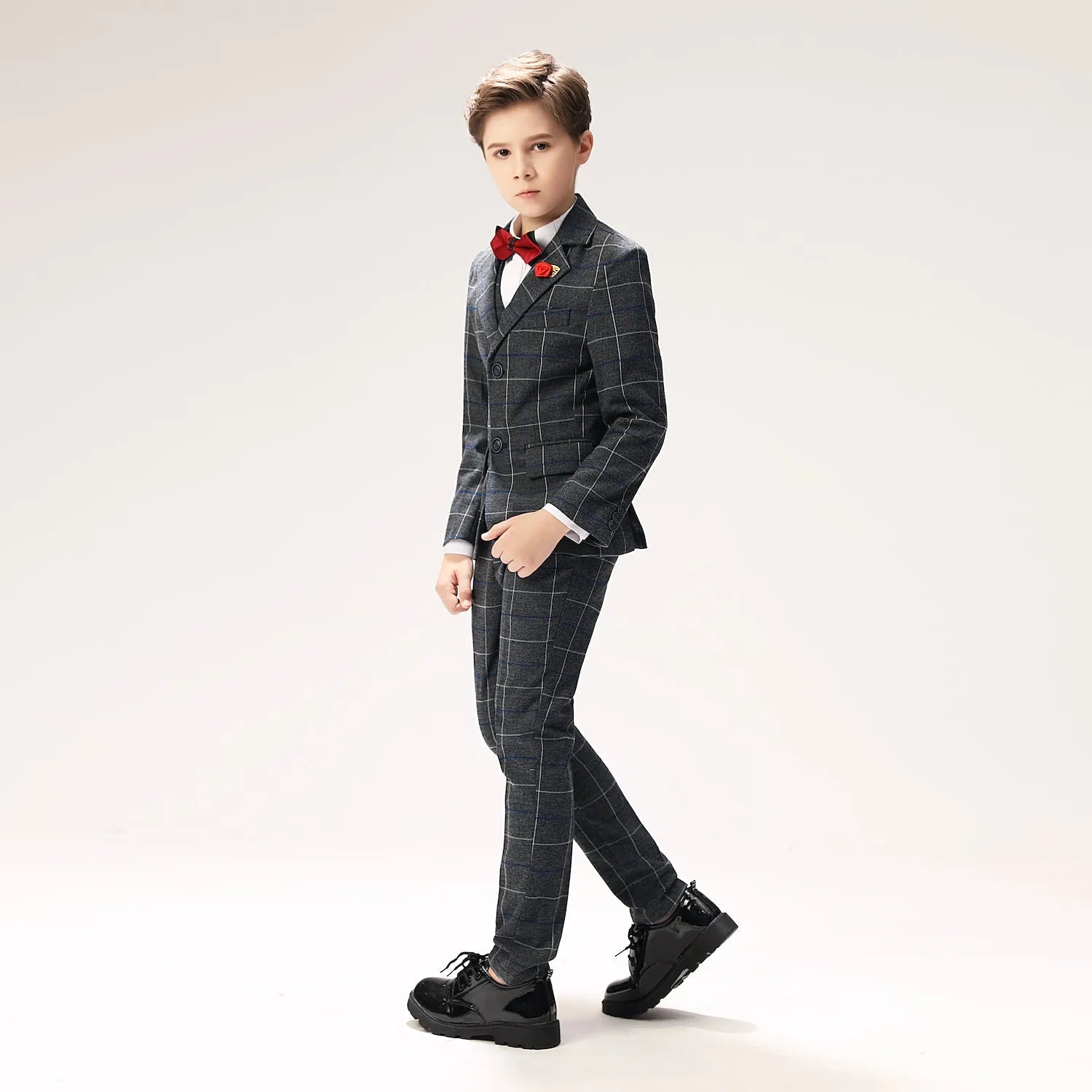 Side angle showing tailored fit of dark grey check boys wedding suit