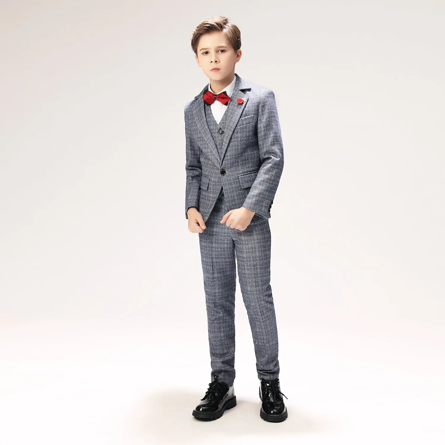 Angled pose showing grey plaid formal boys blazer with red boutonnière and stylish bow tie
