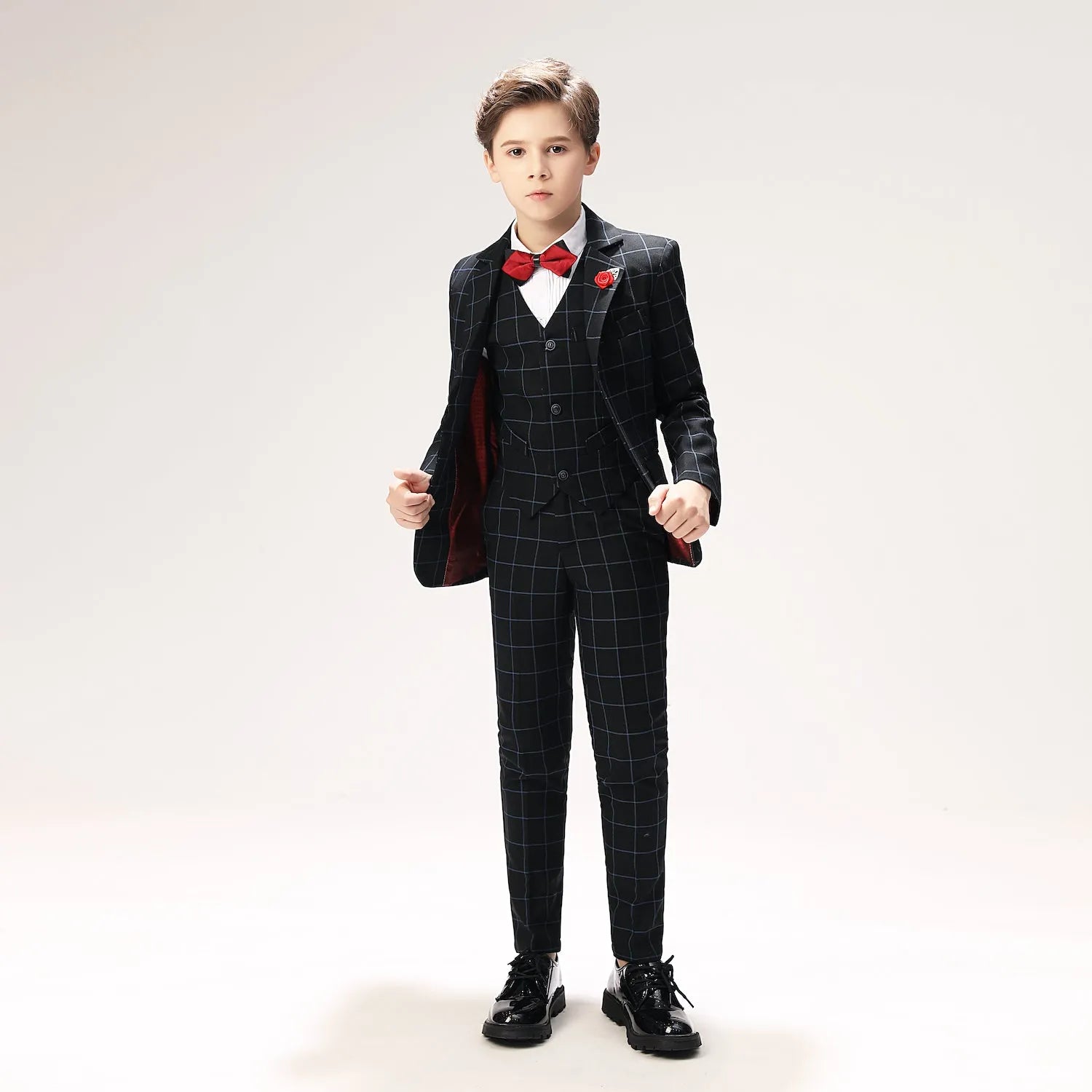 Boys navy plaid suit with red boutonnière and slim fit cut, perfect for events