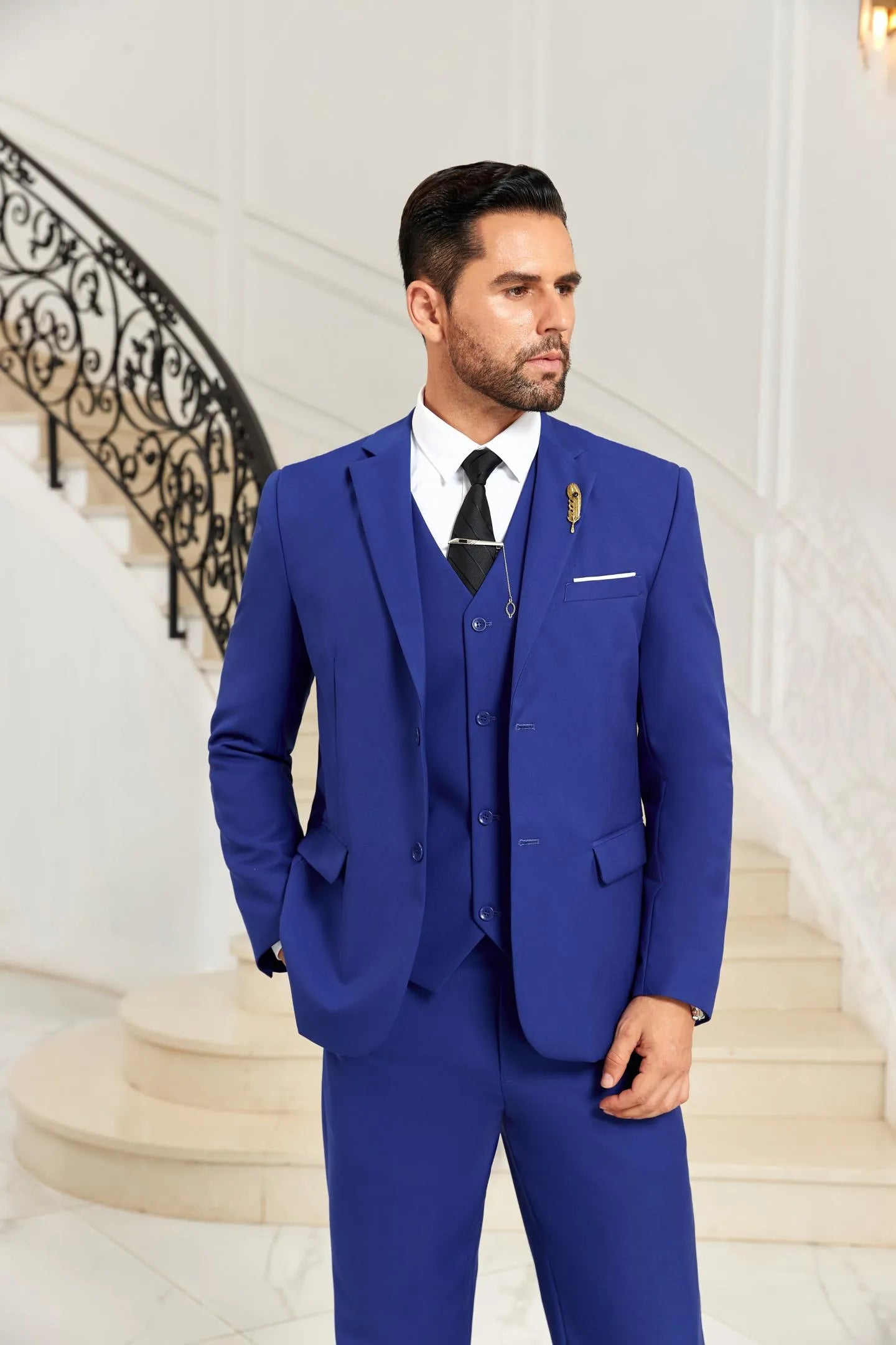 Model wearing blue 3 piece men's suit with blazer and vest, posing in elegant setting for wedding and formal style