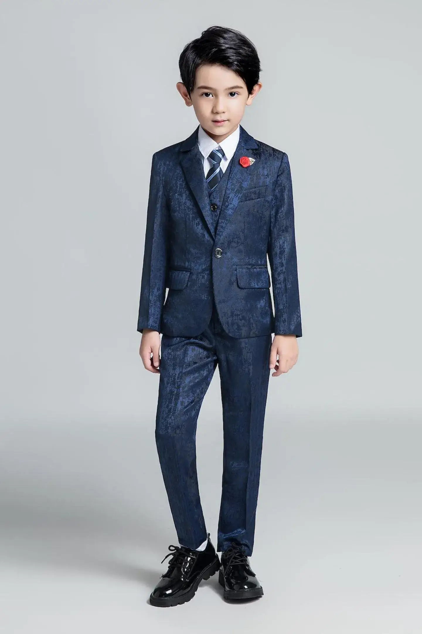 Slim fit dark blue boys' formal suit with textured finish and striped tie, styled for special occasions