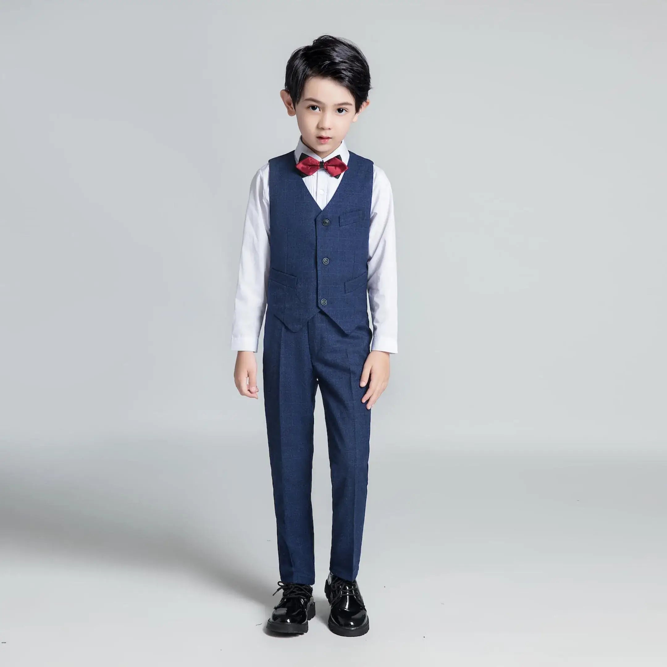 Boy in navy plaid vest and pants with red bow tie – kids’ formal outfit for holidays and weddings