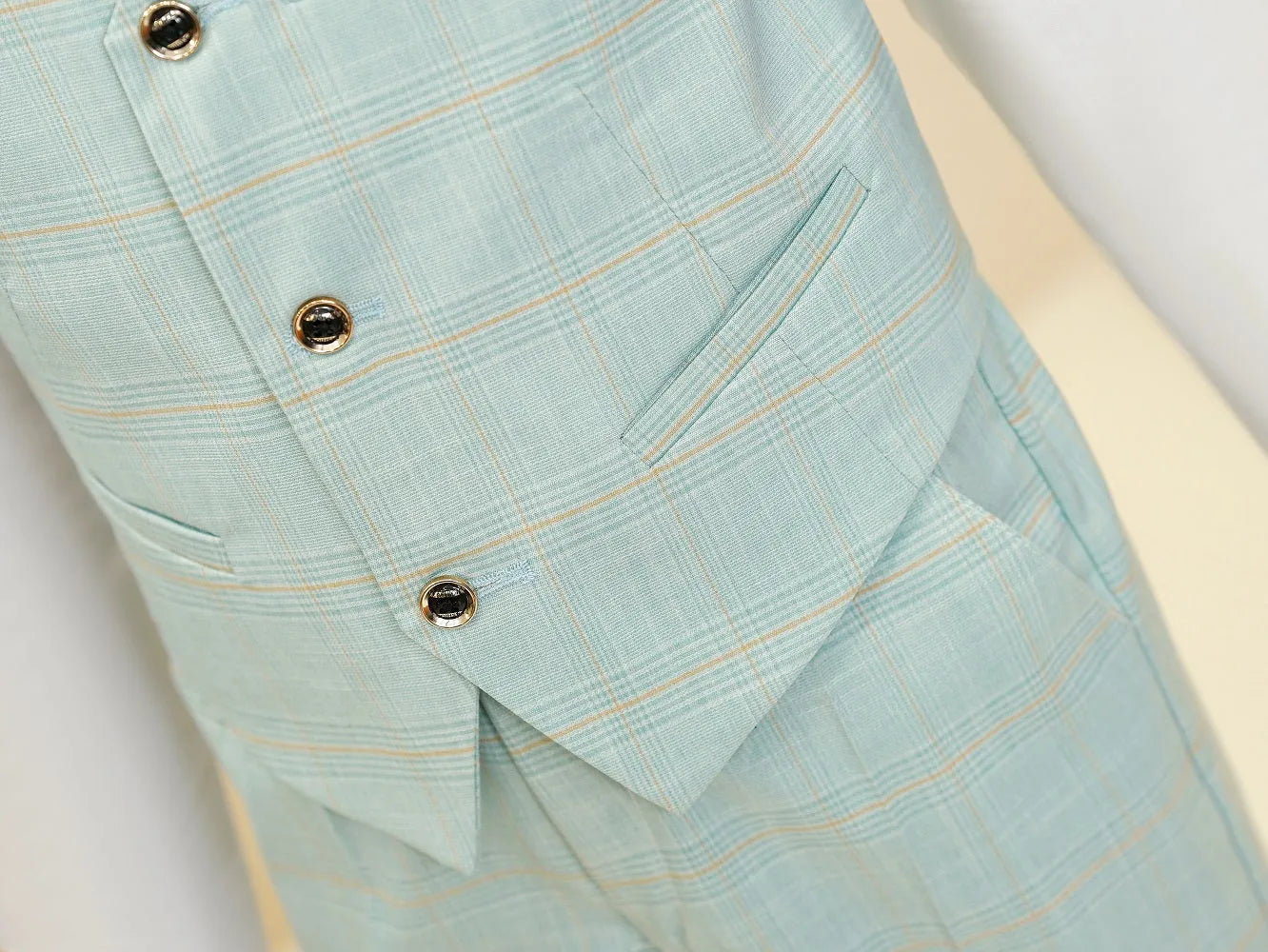 Mint green plaid boys suit: Close-up of black buttons & checked vest pocket detail