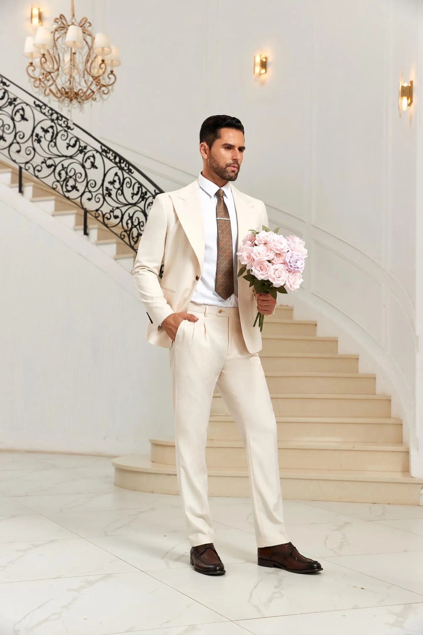 Groom style white 2 piece suit with peak lapel blazer and pants, holding pink bouquet, elegant wedding outfit.