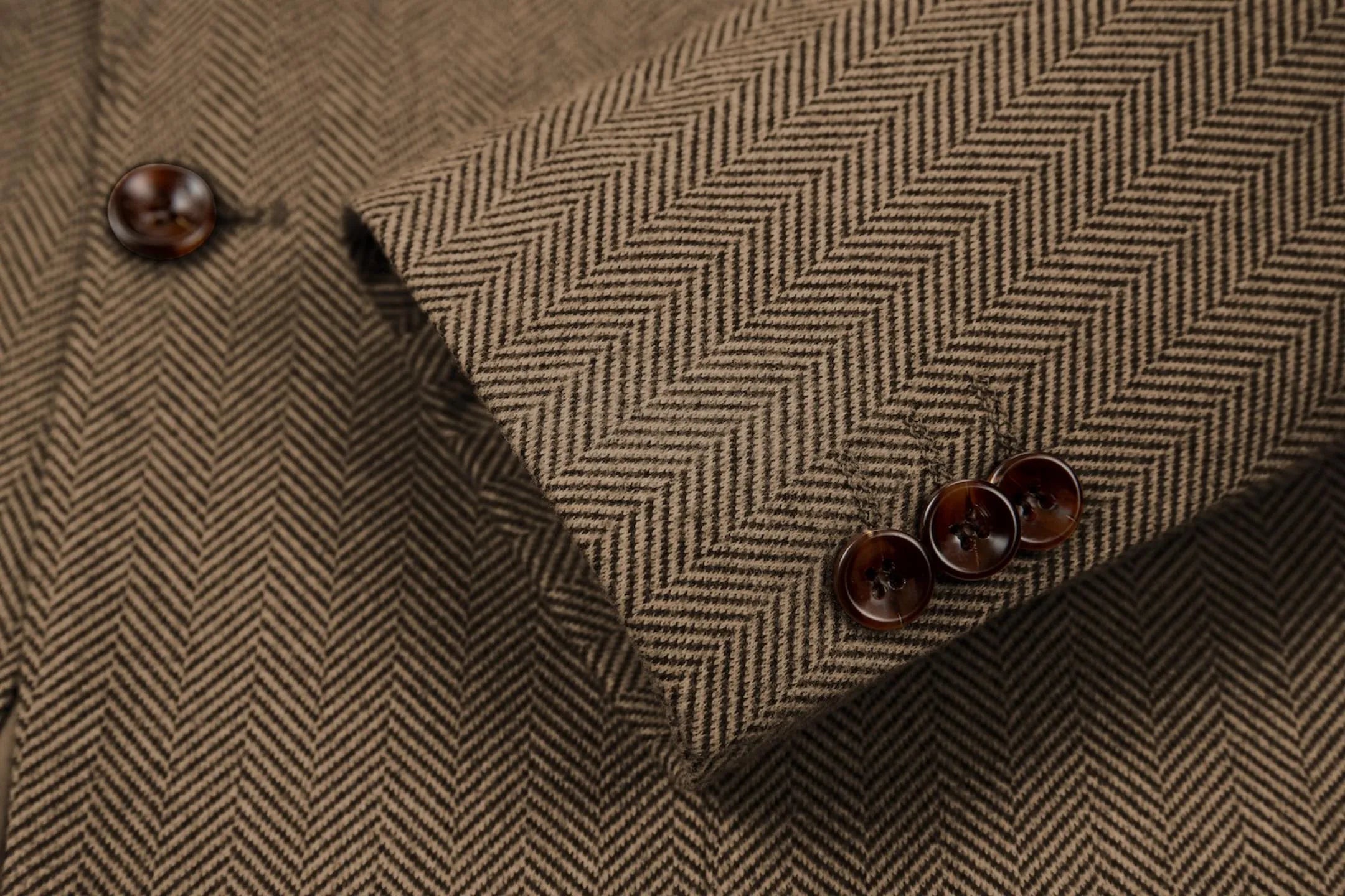 Detailed shot of men's brown herringbone business suit sleeve – showcasing fine tailoring and classic 2-piece style