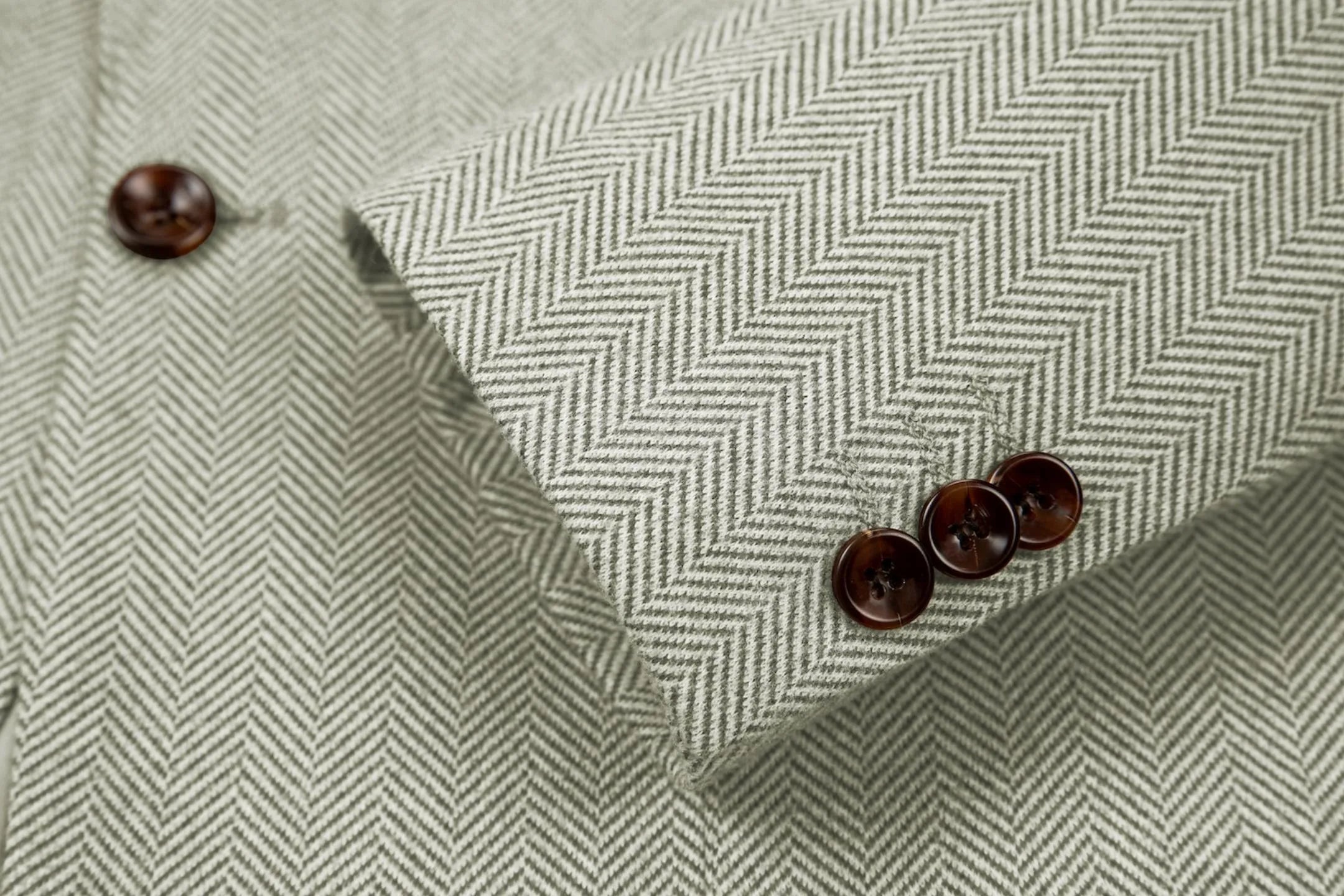 Detailed shot of men's green herringbone business suit sleeve – highlighting fine tailoring and classic 2-piece details