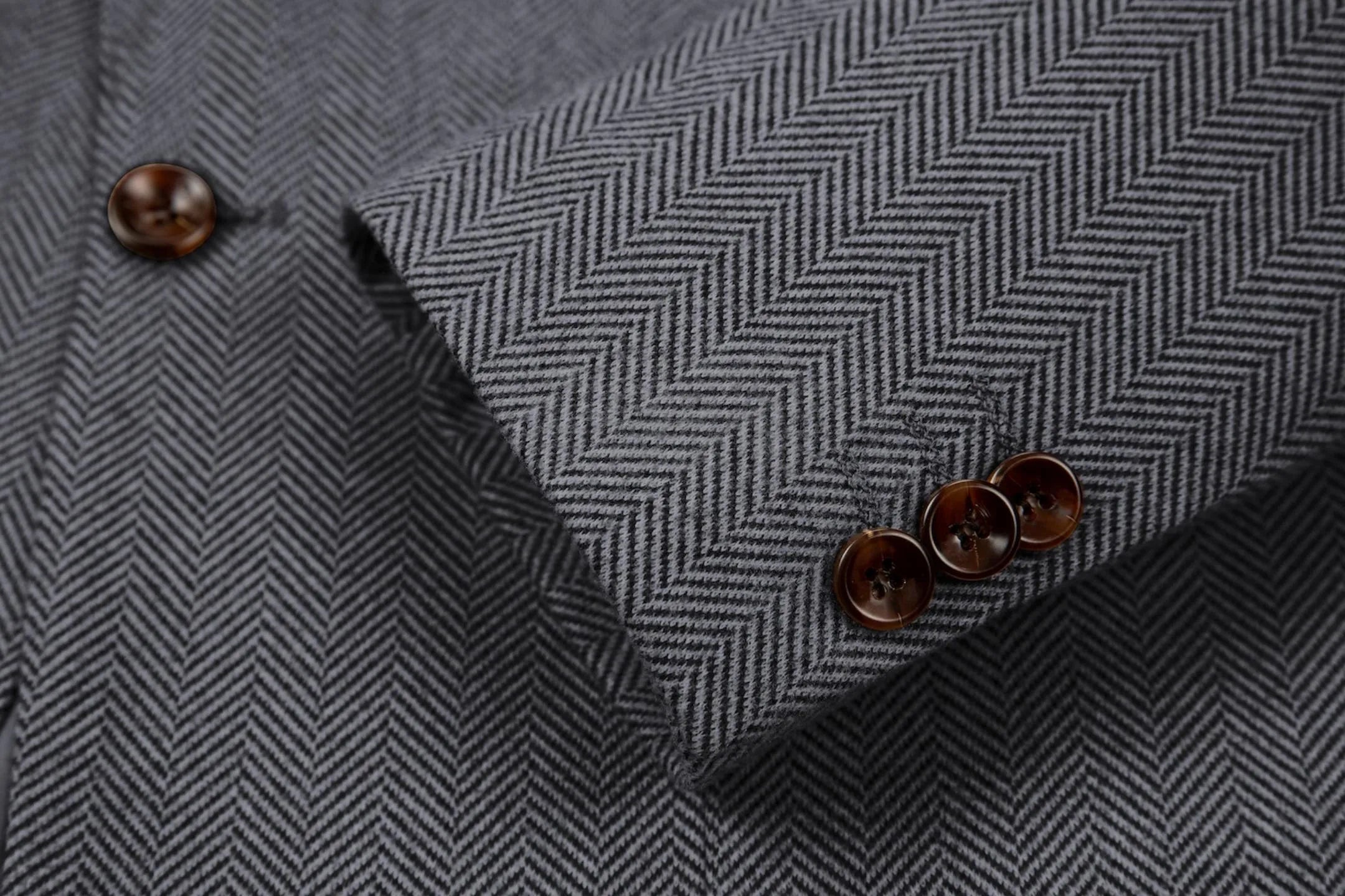 Detailed shot of men's grey herringbone business suit sleeve – showcasing fine tailoring of the 2-piece suit
