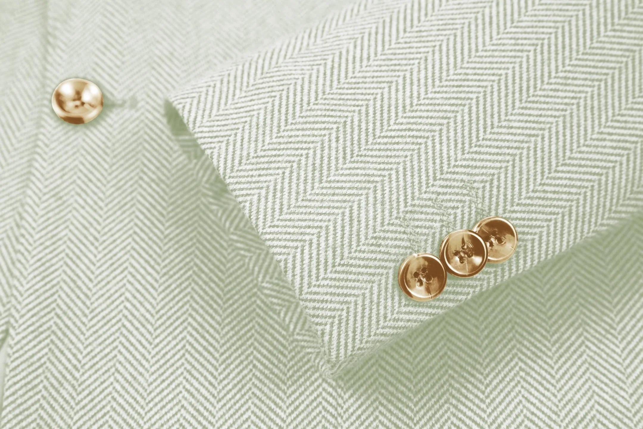 Detailed shot of men's light green herringbone business suit sleeve – emphasizing fine tailoring and classic details