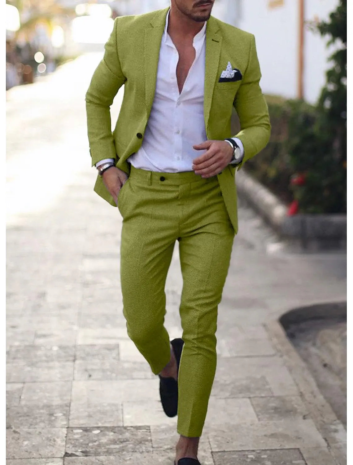Men's sage green linen suit for summer weddings styled with an open white shirt and black loafers.