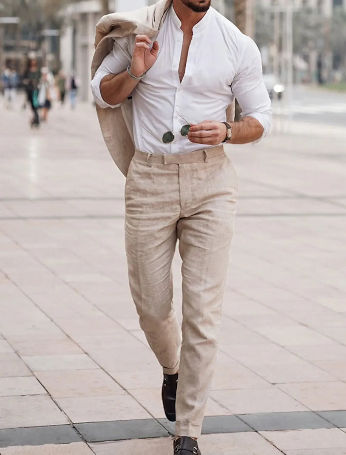 Beige linen pants styled with white mandarin collar shirt and blazer on shoulder