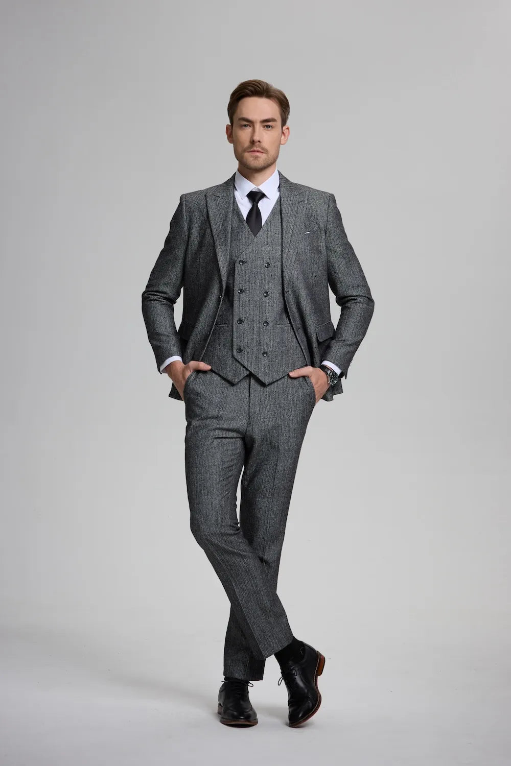 Man wearing a dark gray Versatile Herringbone 3-Piece Suit, featuring a tailored blazer, waistcoat, and trousers.