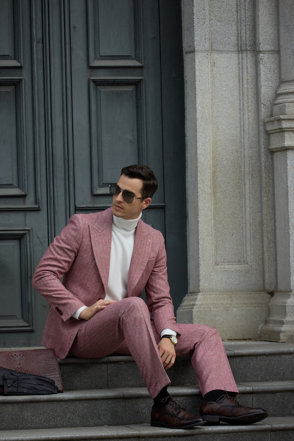 Seated pose in red herringbone suit, paired with white turtleneck and brown shoes