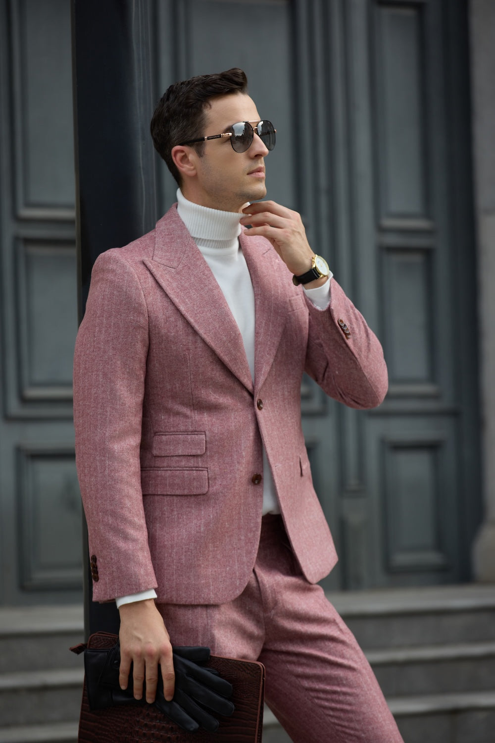 Side profile of red 2 piece herringbone suit styled with sunglasses and gloves