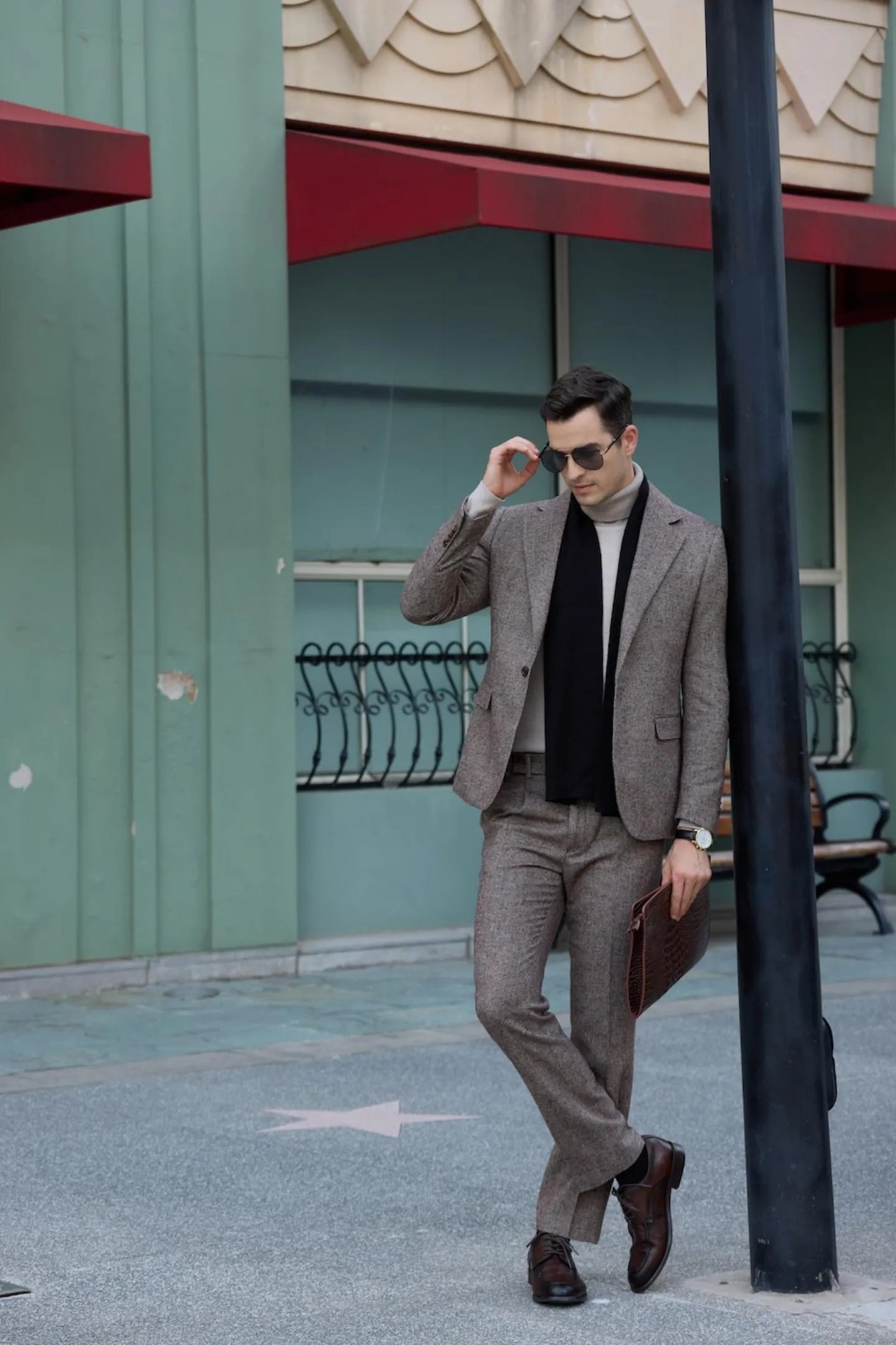 men's brown tweed herringbone 2-piece suit with black scarf, standing near a pole outdoors, with a business casual style.