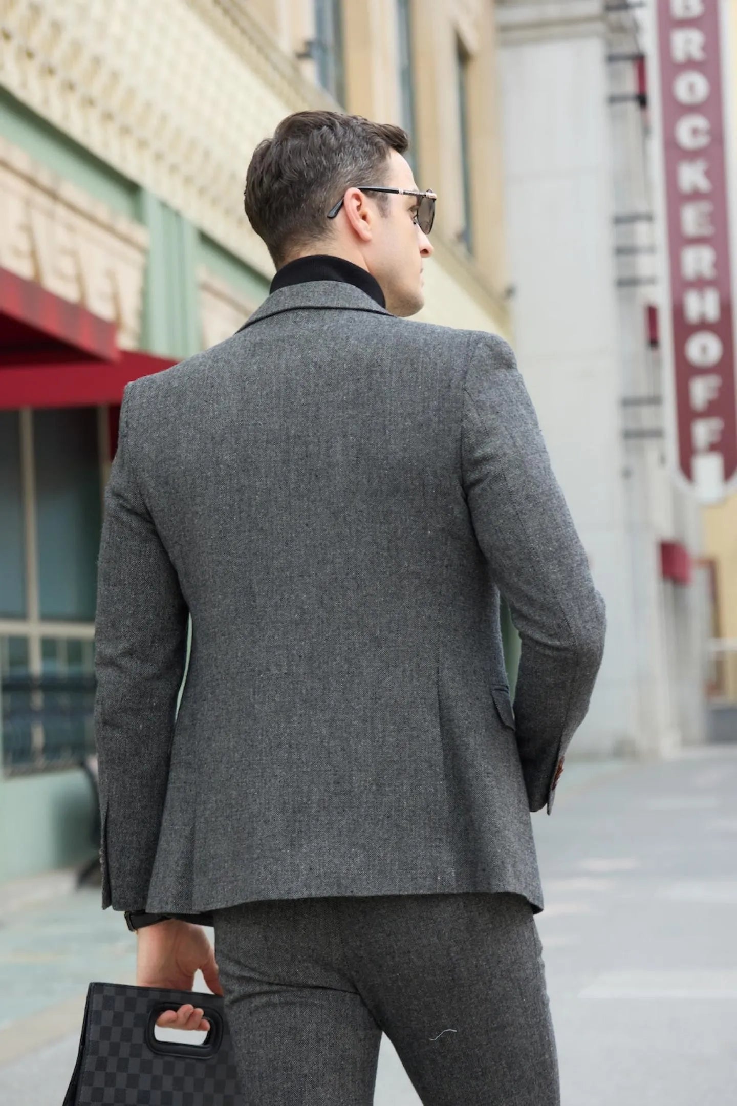 back view of men's dark grey tweed herringbone 2 piece suit, featuring slim fit and brown shoes.