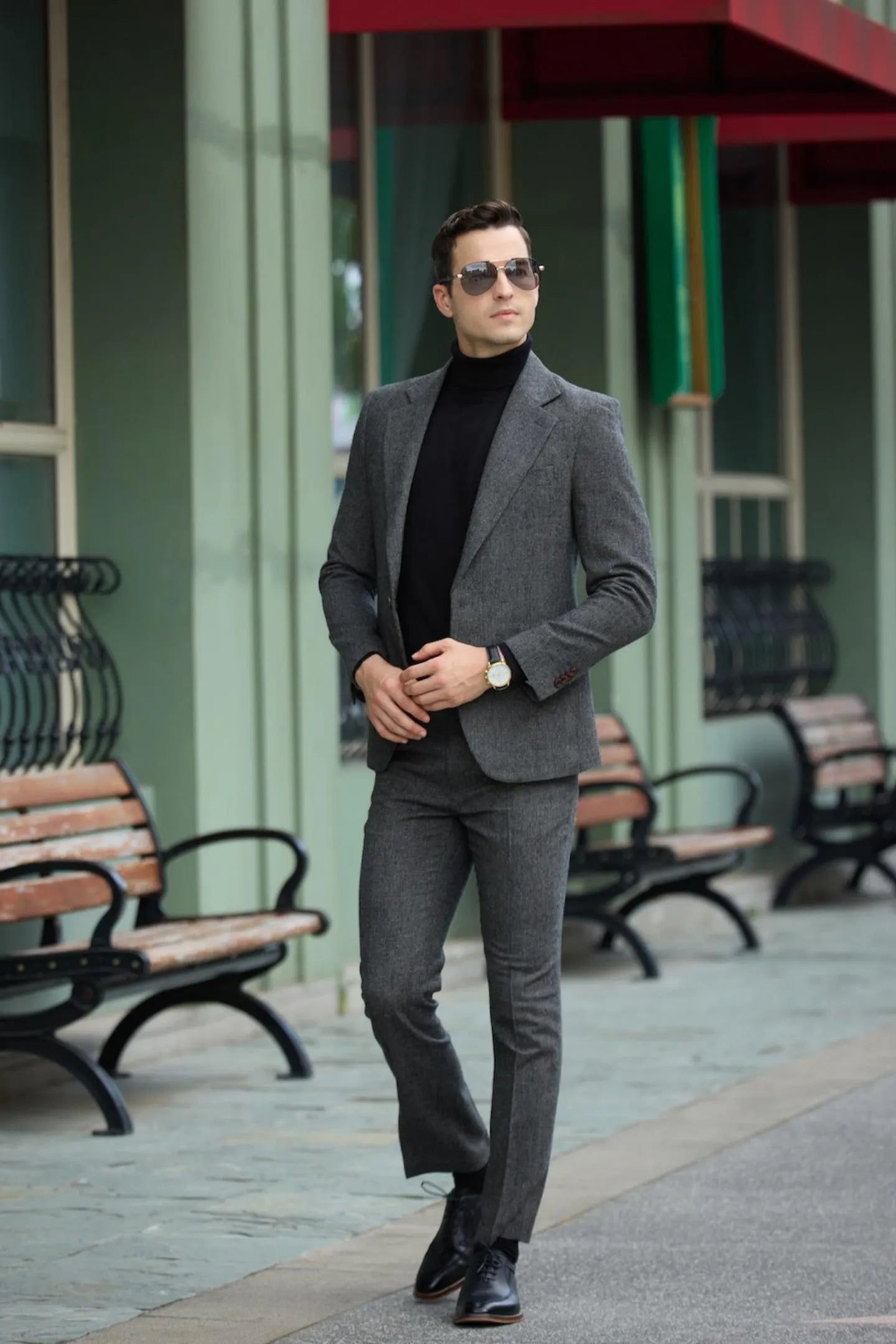 side view of men's dark grey tweed herringbone 2 piece suit with slim fit, accessorized with black turtleneck and shoes.