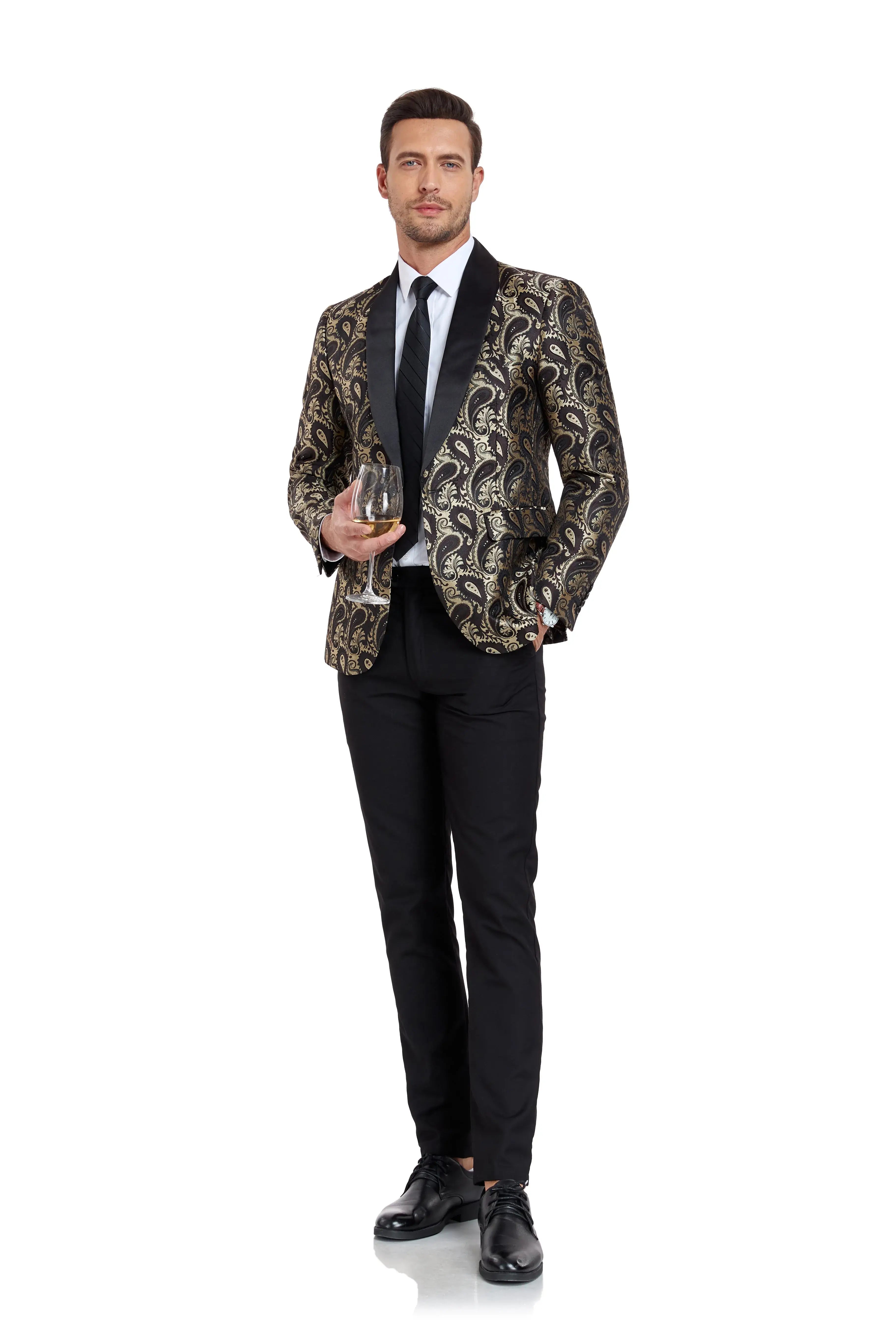 A man posing in a black and gold paisley patterned blazer with black trousers, giving a stylish look with a confident stance.