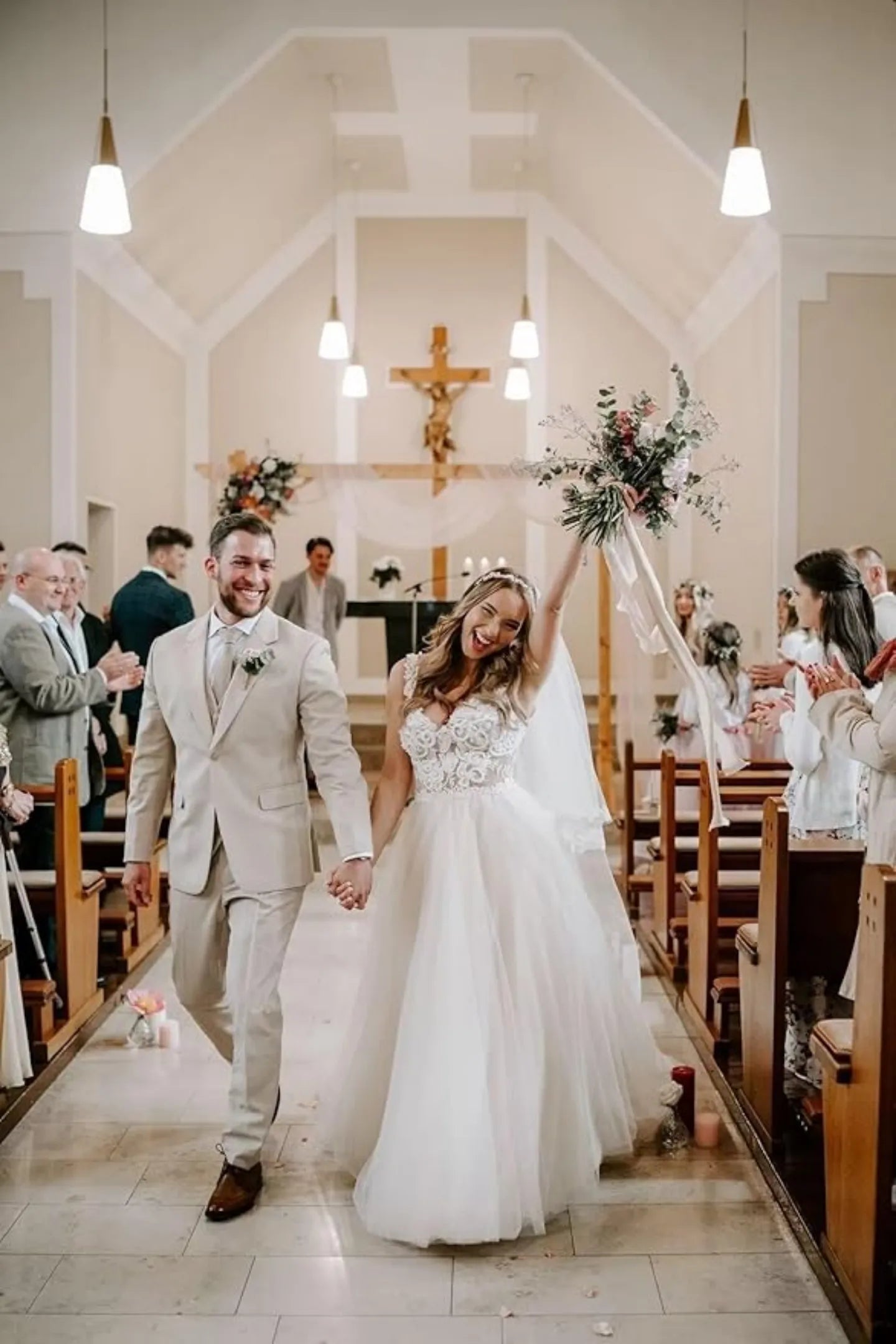 beige groom suit with vest worn at indoor wedding ceremony with happy couple walking