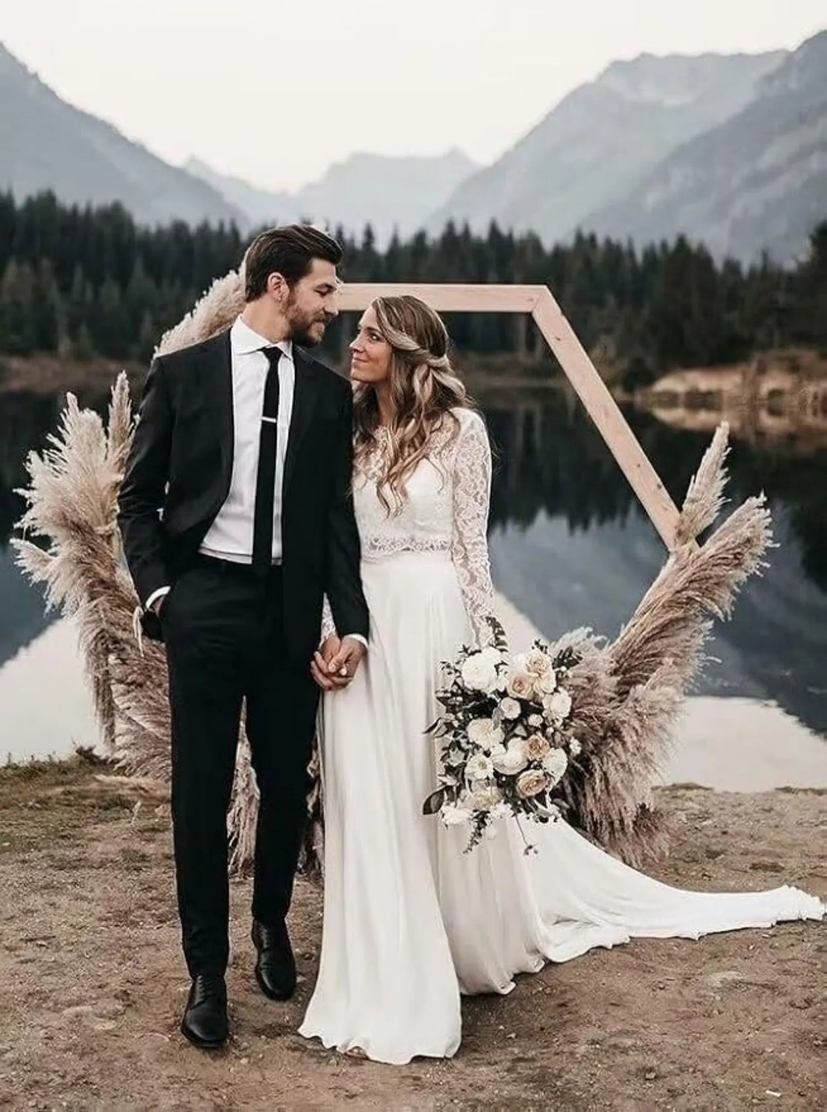 groom in slim fit black tuxedo with white shirt and tie at lakeside wedding