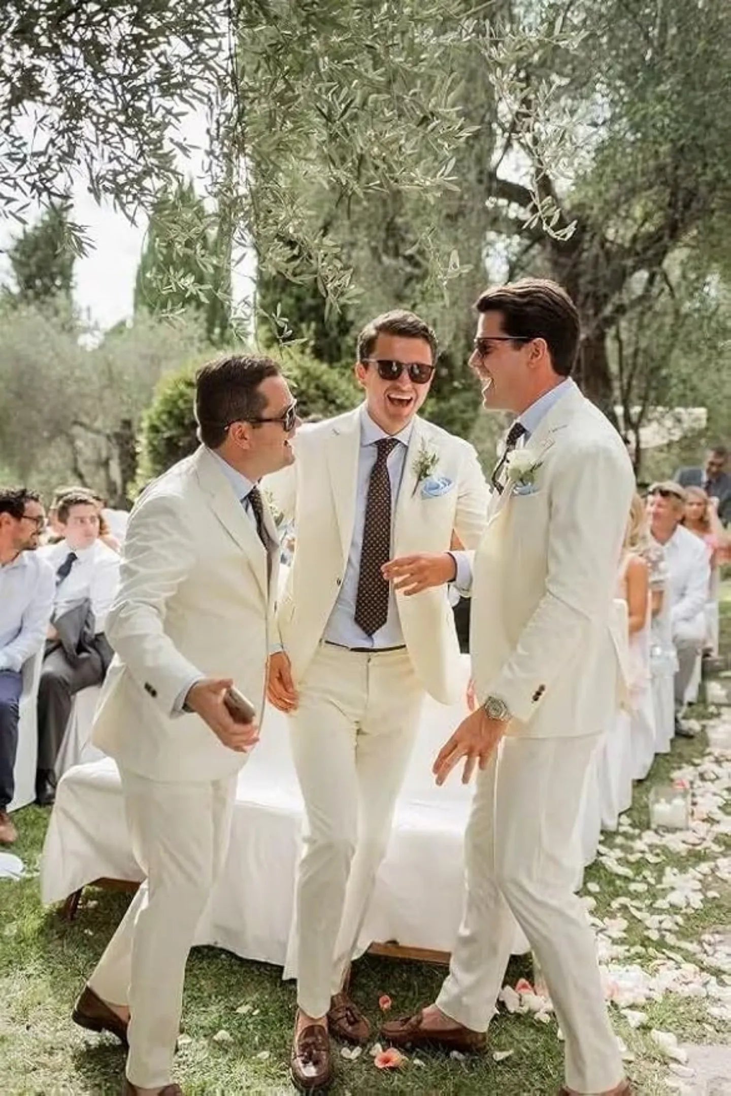 groomsmen in ivory cream summer wedding suits with blue boutonnieres