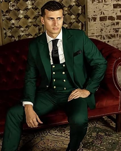 Man in emerald green 3-piece suit with gold buttons, sitting on red velvet sofa against brick wall