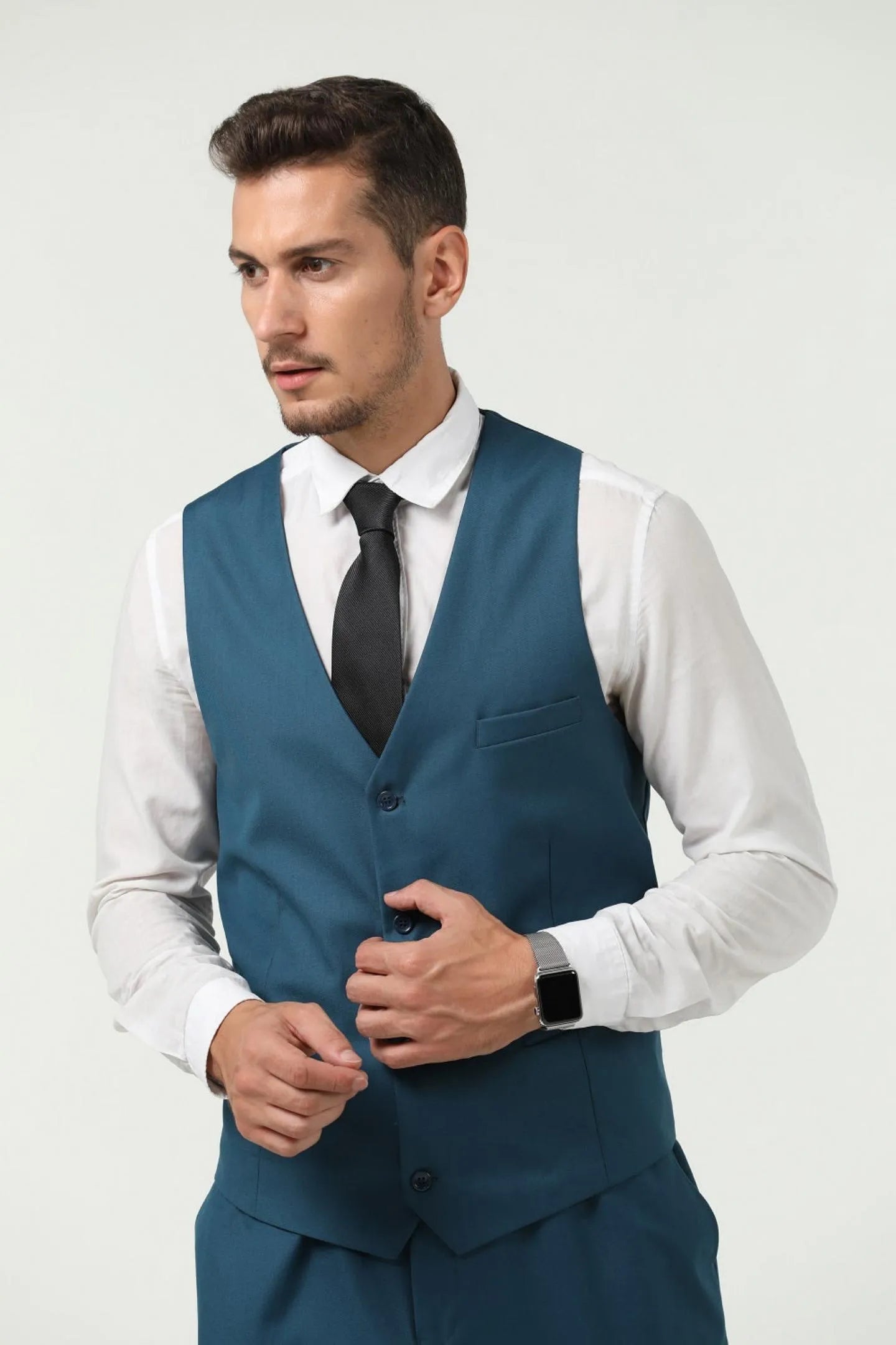 side angle of a man in a lake blue slim fit two-button 3-piece suit, wearing the vest and trousers, with hands placed in pockets.